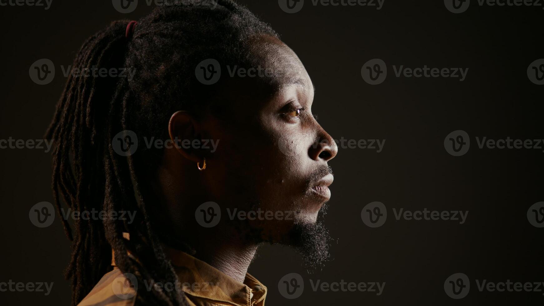 Stylish male model acting surprised and amazed by view, seeing something and being shocked. African american guy admiring a thing and saying wow in studio with black background. photo