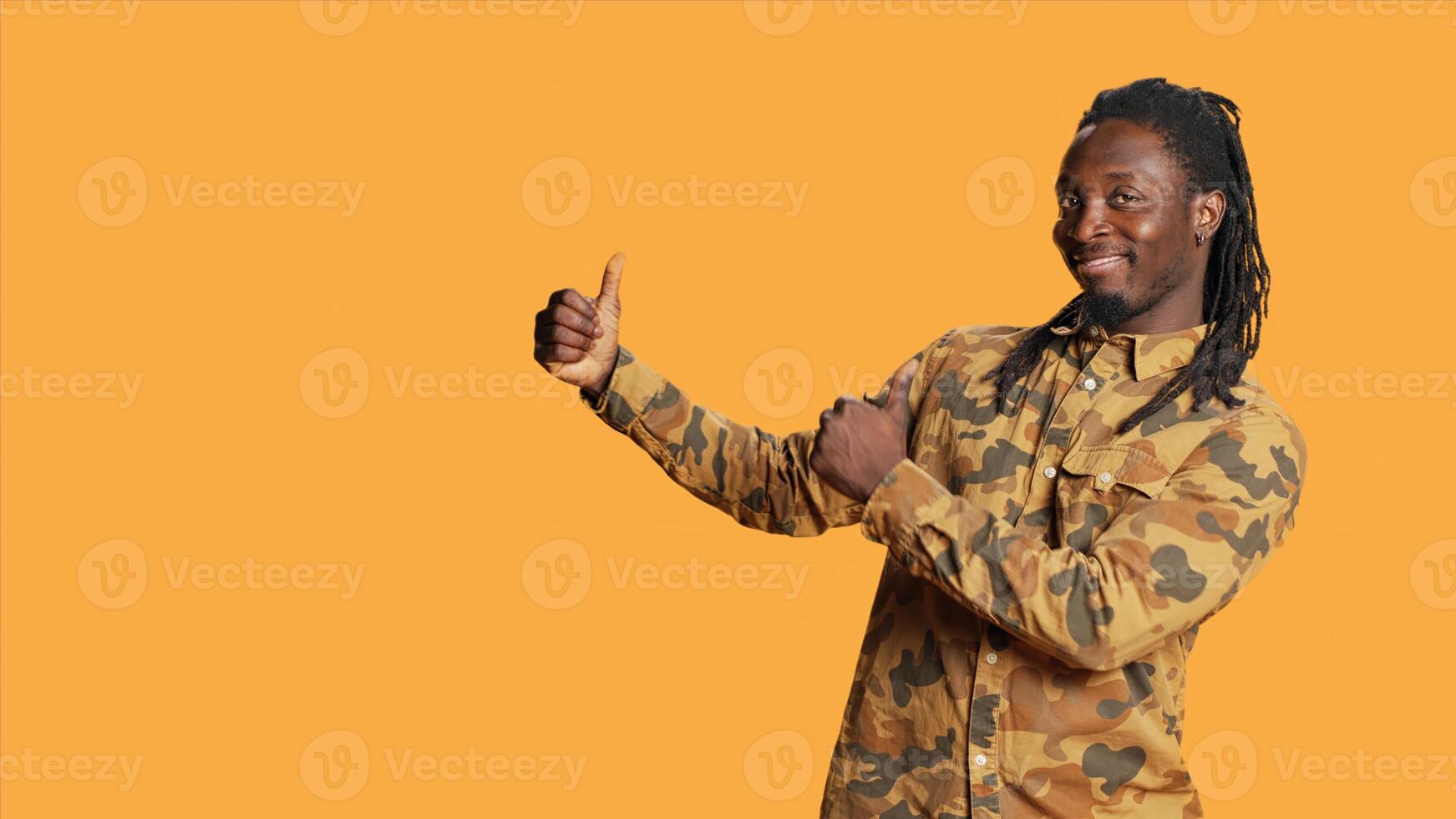 Male model pointing at promotional marketing ad in studio, creating web advertisement for new online campaign. Young adult posing over orange background, shows left or right directions. photo