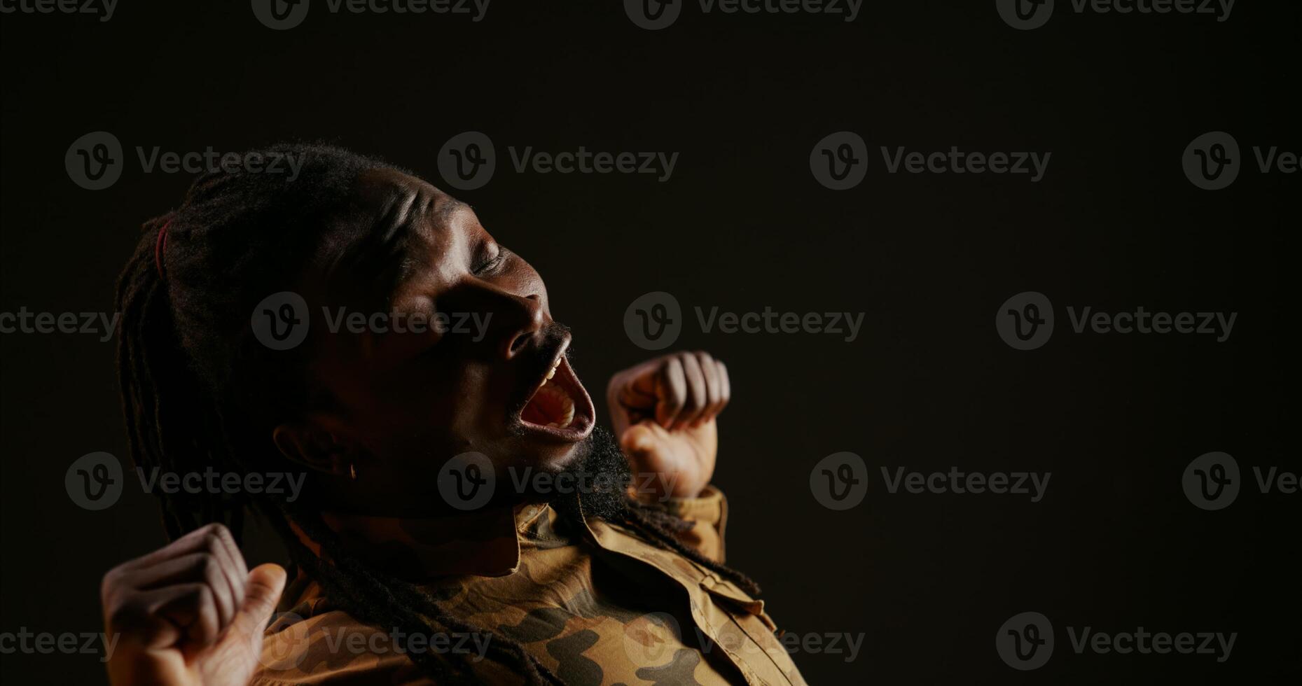 Lazy male model feeling sleepy on black background, experiencing burnout and almost falling asleep in studio. Young adult being extremely tired, dealing with exhaustion and fatigue. photo