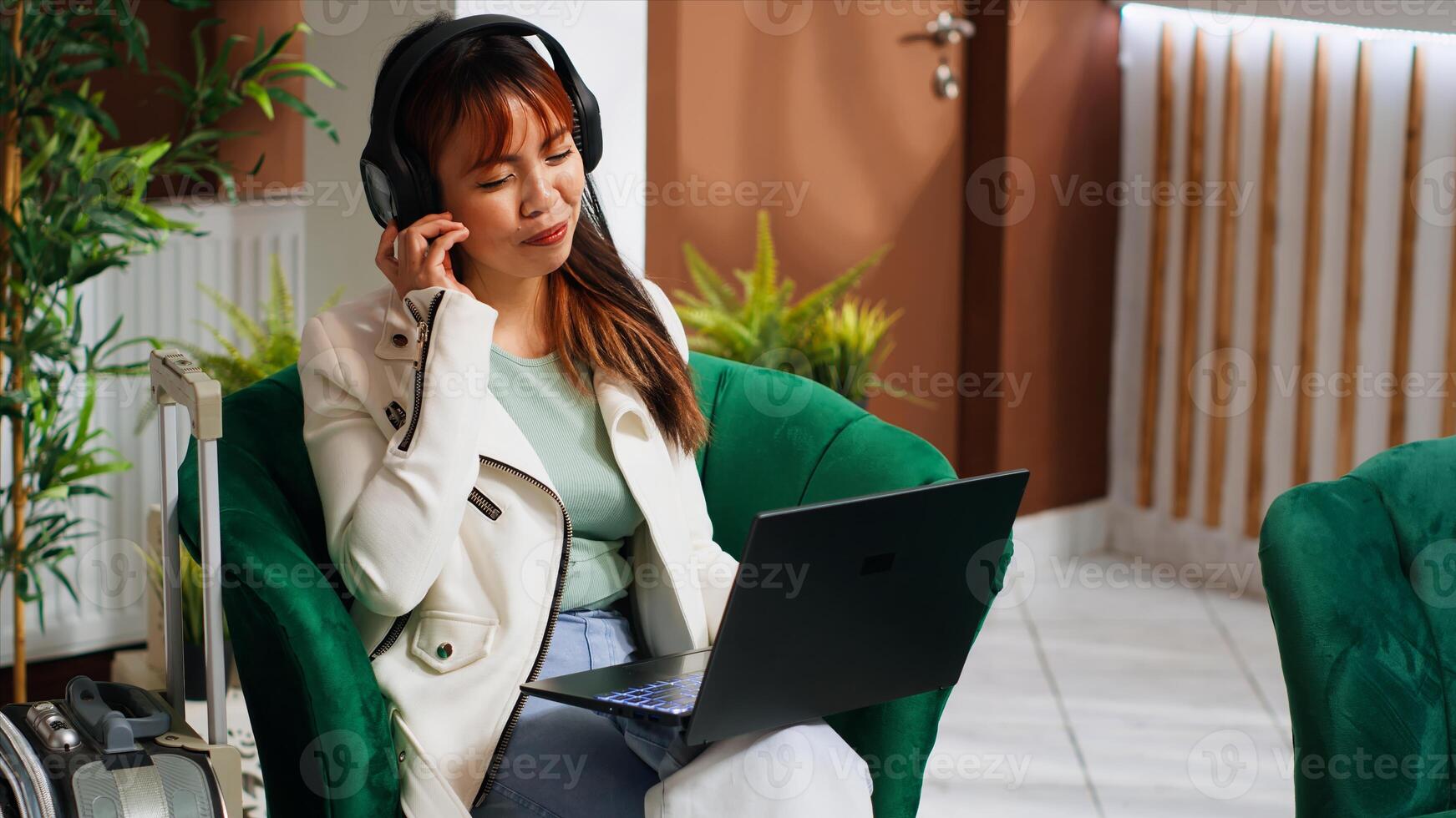 hotel invitado acecho películas en ordenador portátil en salón área, llegando temprano a cinco estrella recurso y esperando para alojamiento a ser disponible. joven mujer disfrutando hora apagado en día festivo. foto