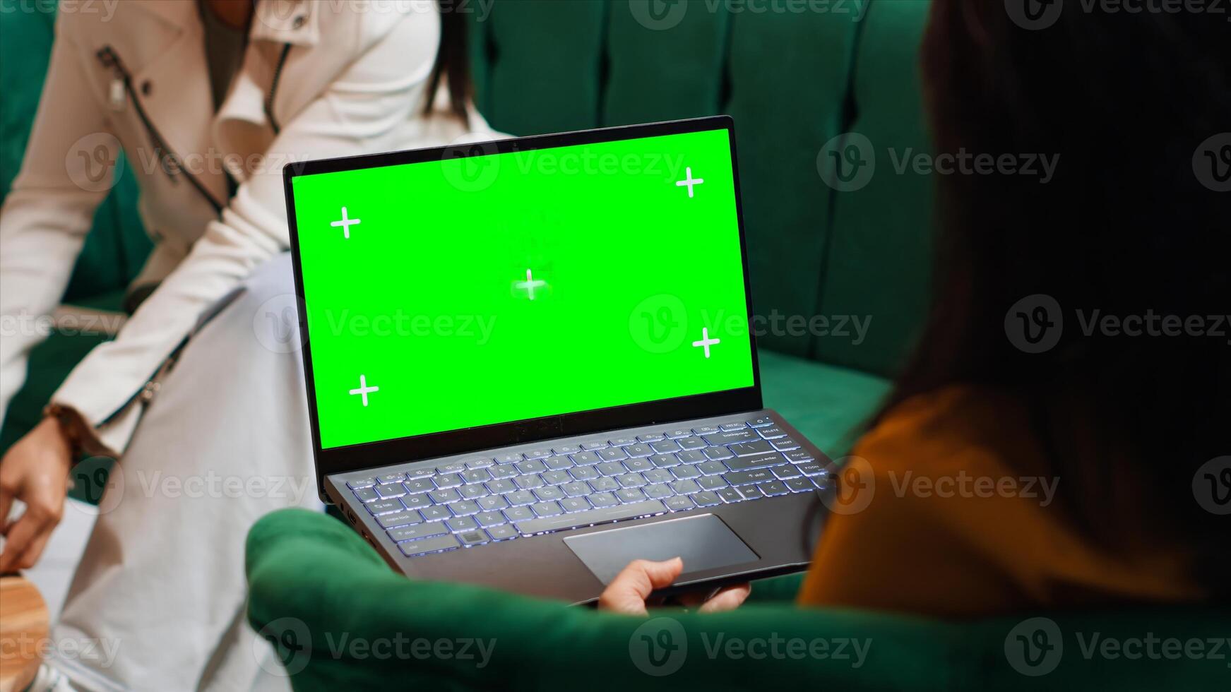 Hotel guest using laptop with greenscreen layout in lobby, looking at copyspace chromakey display in lounge area. Modern person holding pc showing isolated mockup template on screen. photo