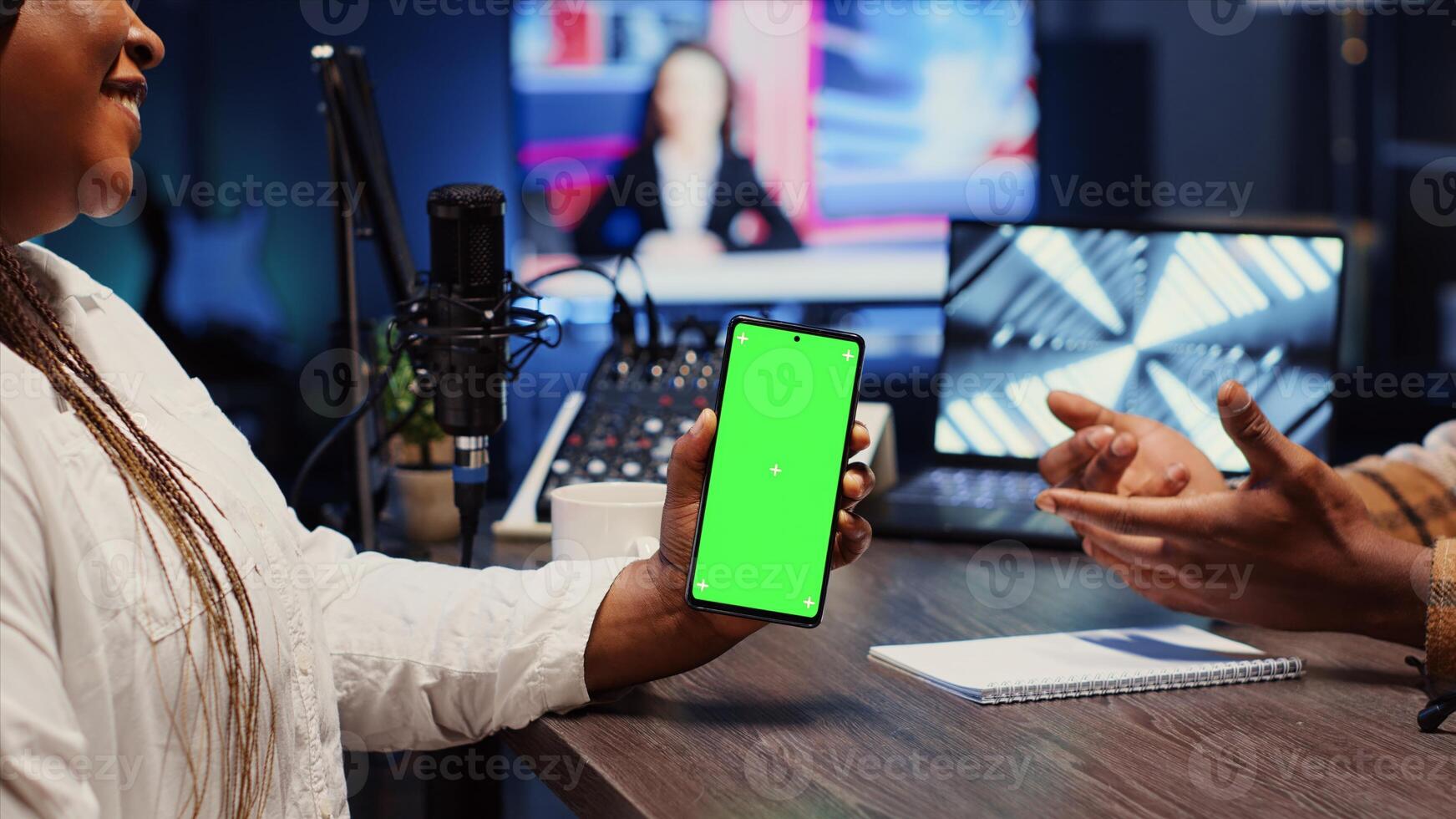 Green screen smartphone in front of show presenter recording podcast, enjoying cup of coffee and nice conversation with guest. Mockup mobile phone in studio used for live broadcast with woman photo