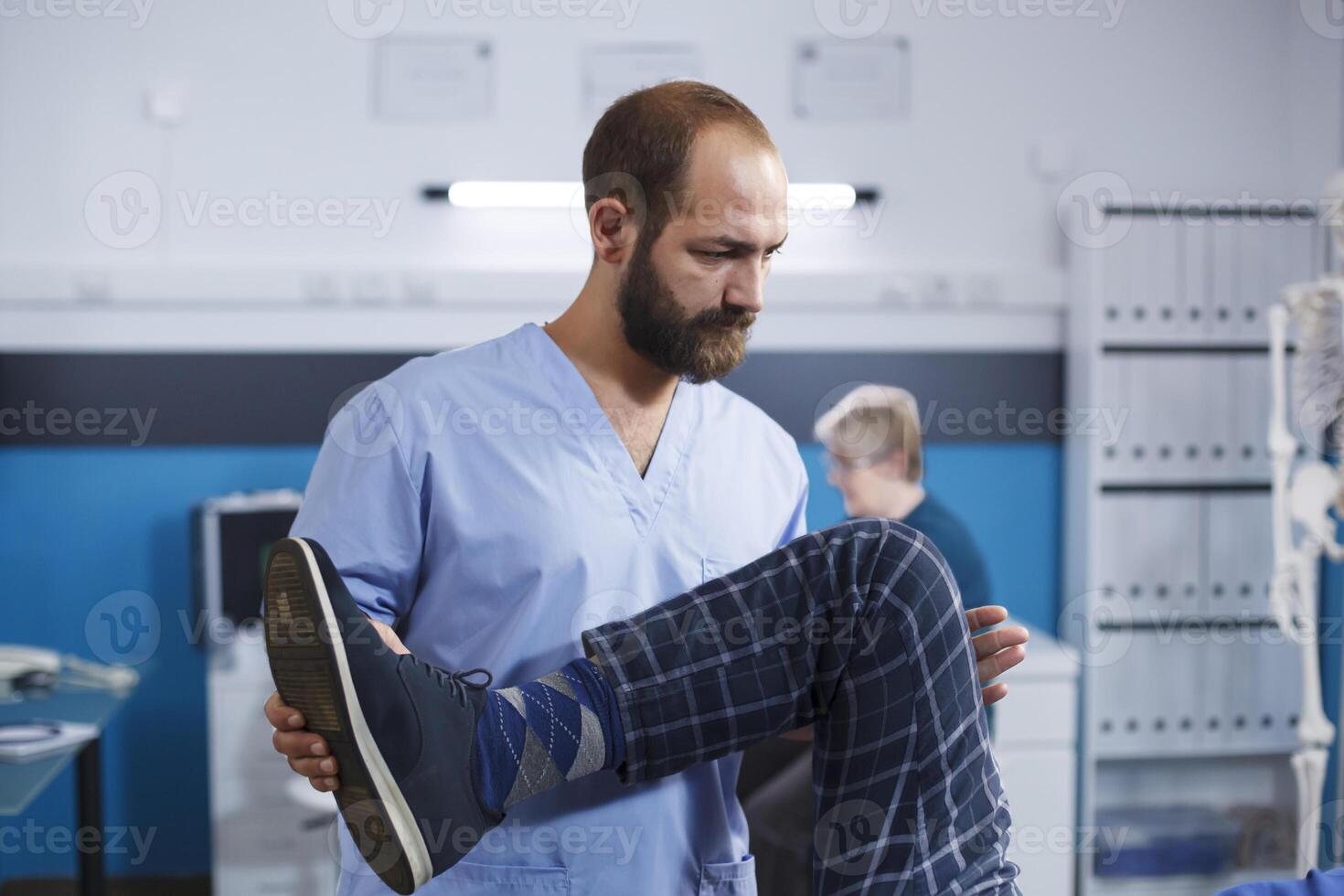 Close-up of orthopedic nurse assisting patient with knee injury at physical therapy. Male medical specialist providing osteopathy care to a man suffering from leg muscular discomfort. photo