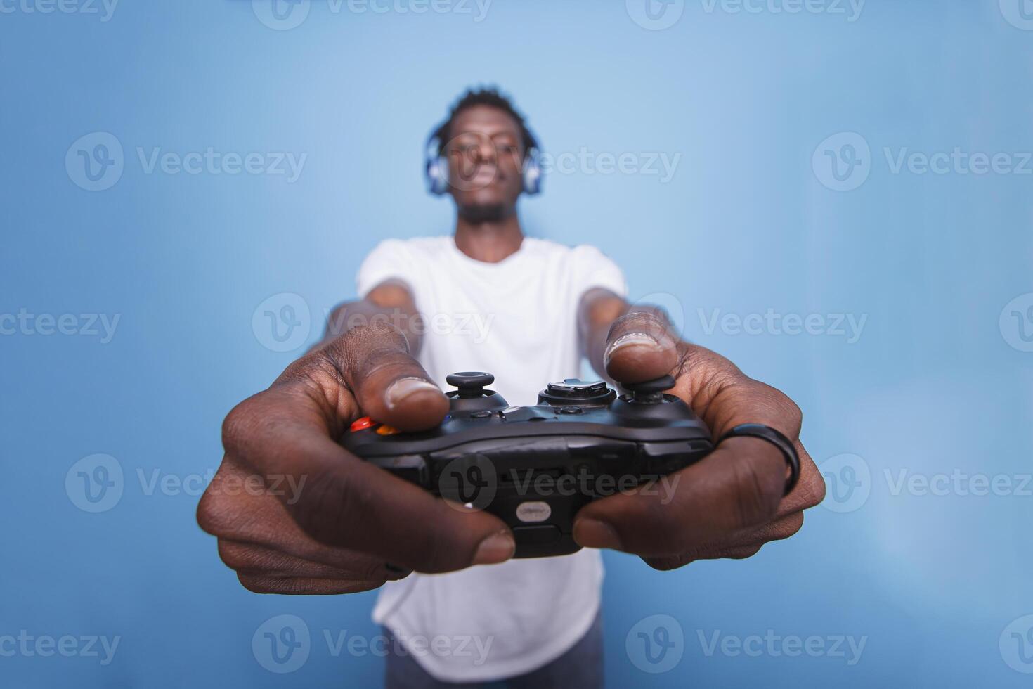 African american male individual wearing a headset and using a controller to play video games. Young black man playing a game with a joystick while listening to music with headphones. photo