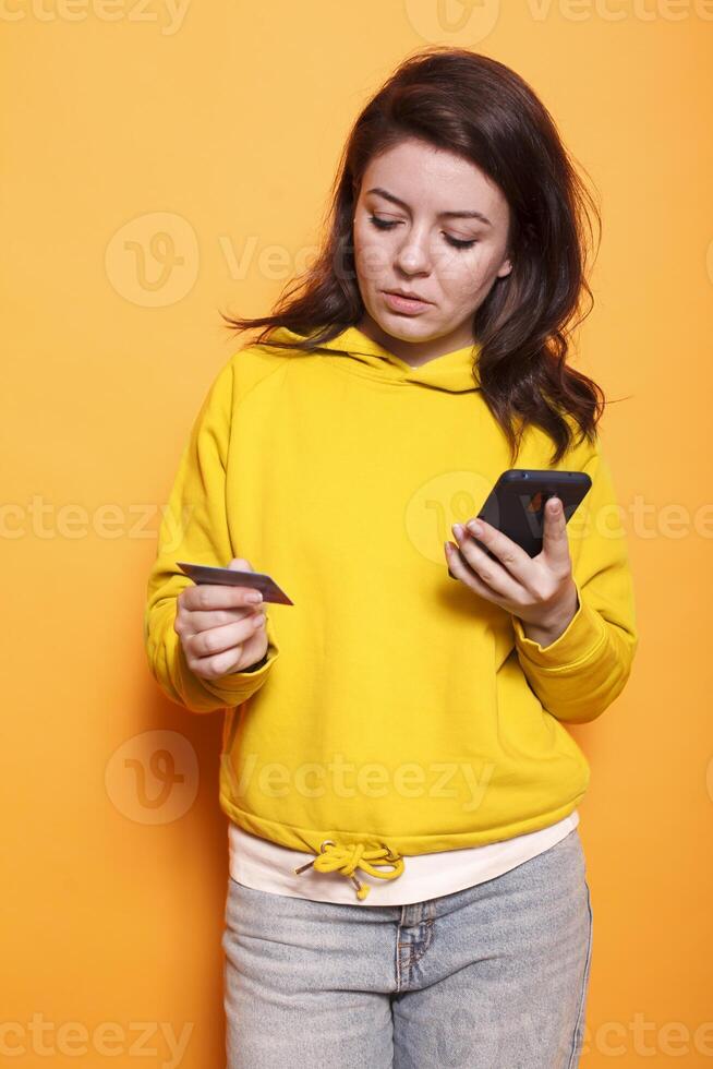 Woman using smartphone to shop online is having problems inputting credit card information. Young female person using a mobile phone to order products while holding her bank card. photo