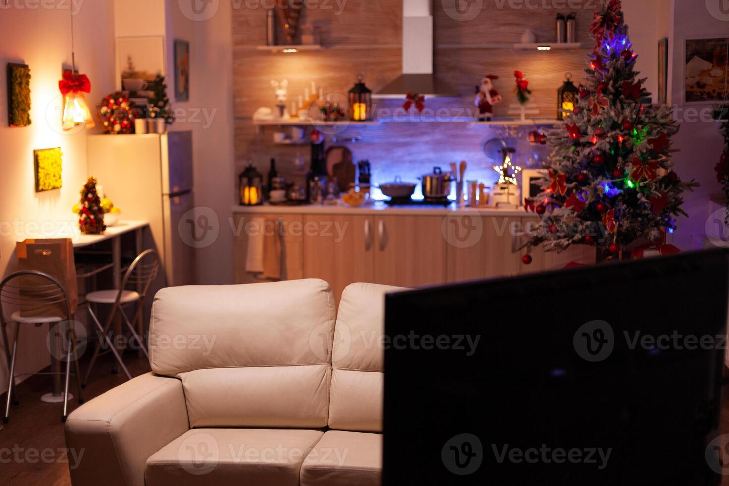 Empty xmas living room with nobody in it ready for winter holiday at home. In background x-mas decorated kitchen with modern furniture. Christmas decorations at home. Christmas festive ornaments photo