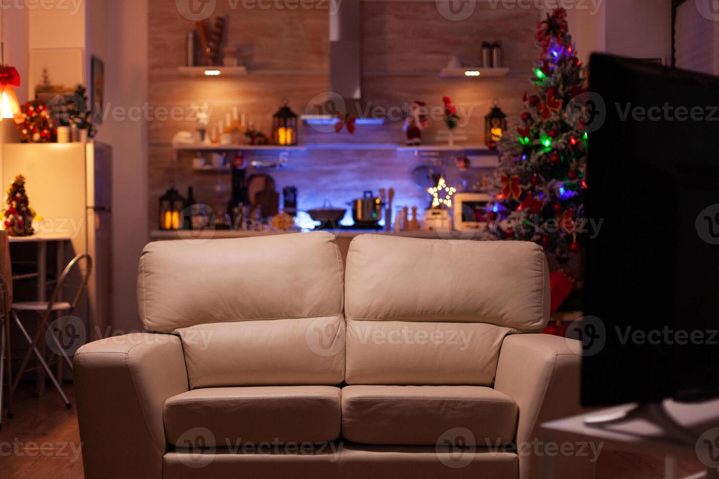 Empty living room with modern furniture ready for christmas holiday. In background x-mas decorated kitchen during winter season waiting for guest. Stylish christmas decorations. New year ornament photo
