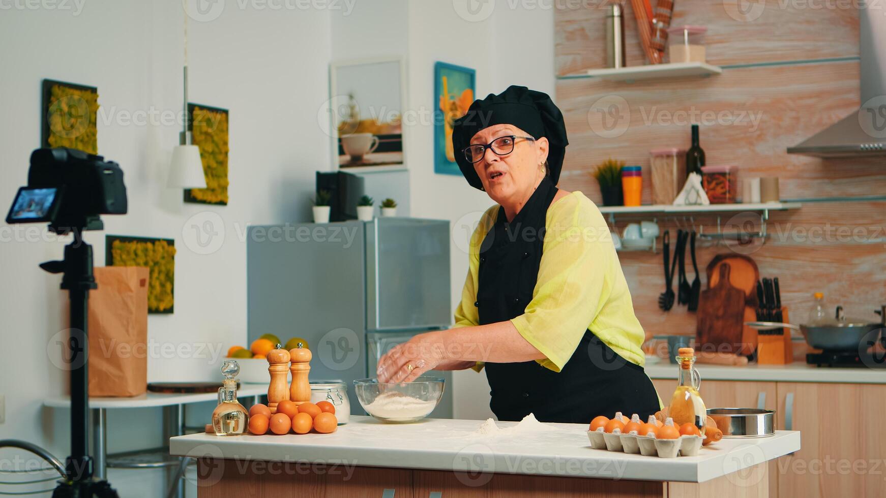 Woman baker presenting recipe while recording tutorial for social media. Retired blogger chef influencer using internet technology communicating, shooting, blogging on podcast with digital equipment photo