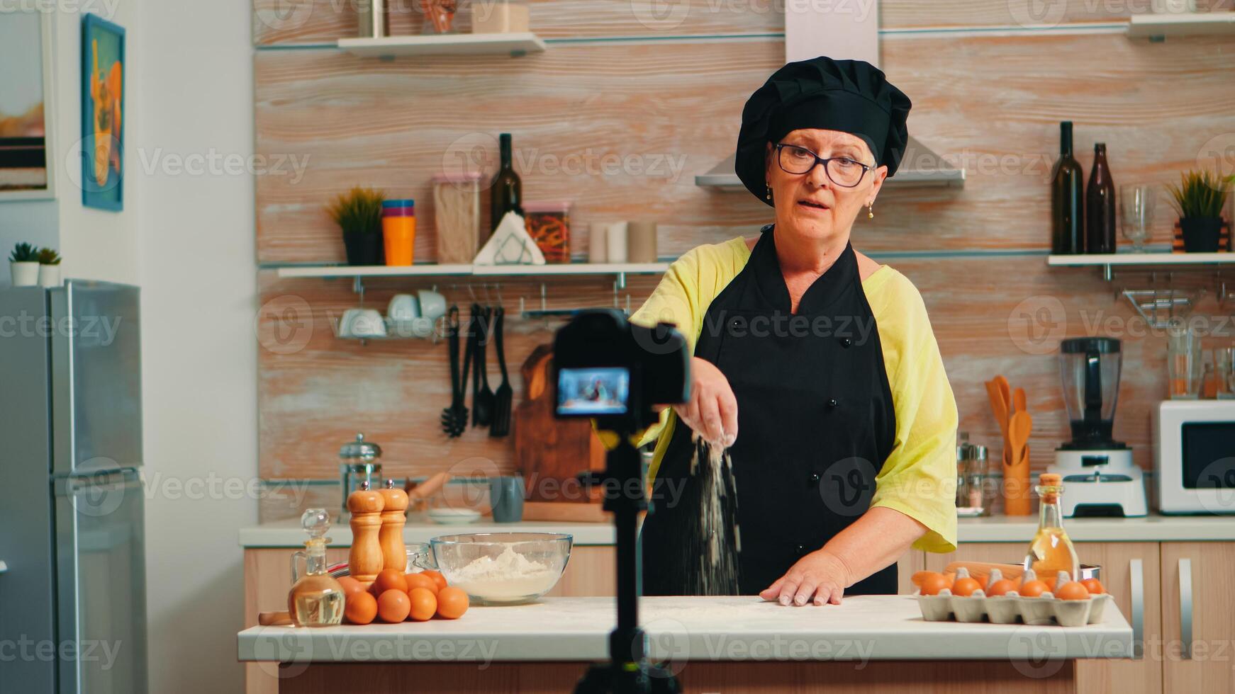 Tutorial about flour while recording food preparation in home kitchen. Retired blogger chef influencer using internet technology communicating, shooting blogging on social media with digital equipment photo