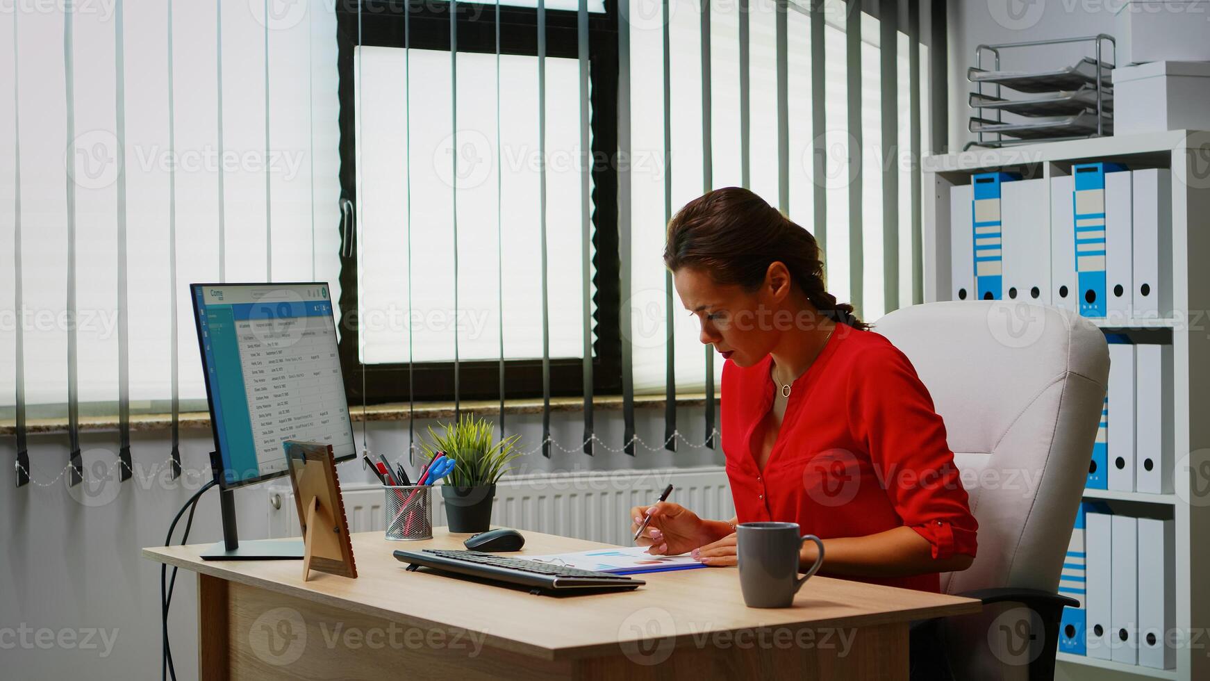 Young employee checking clipboard information looking on pc desktop. Hispanic entrepreneur working in modern professional office, workplace in personal corporate company typing on computer keyboard photo