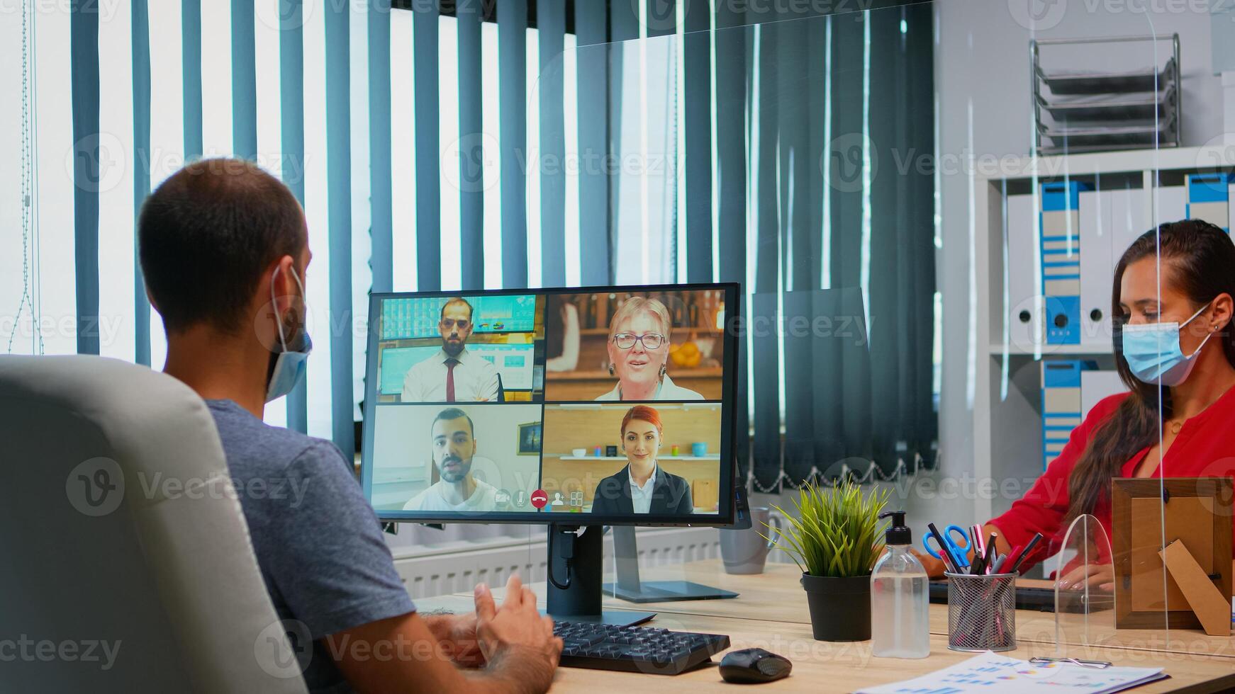 hombre con proteccion máscara participativo a en línea grupo vídeo conferencia en nuevo normal oficina. persona de libre dedicación trabajando en lugar de trabajo chateando hablando teniendo virtual reunión, utilizando Internet tecnología foto