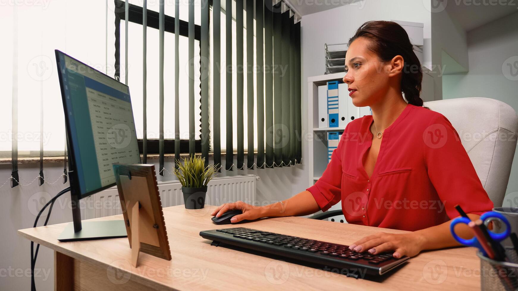 Leader writing on computer sitting alone in modern office room. Hispanic entrepreneur comming at work, in professional company workspace typing on computer keyboard looking at desktop photo