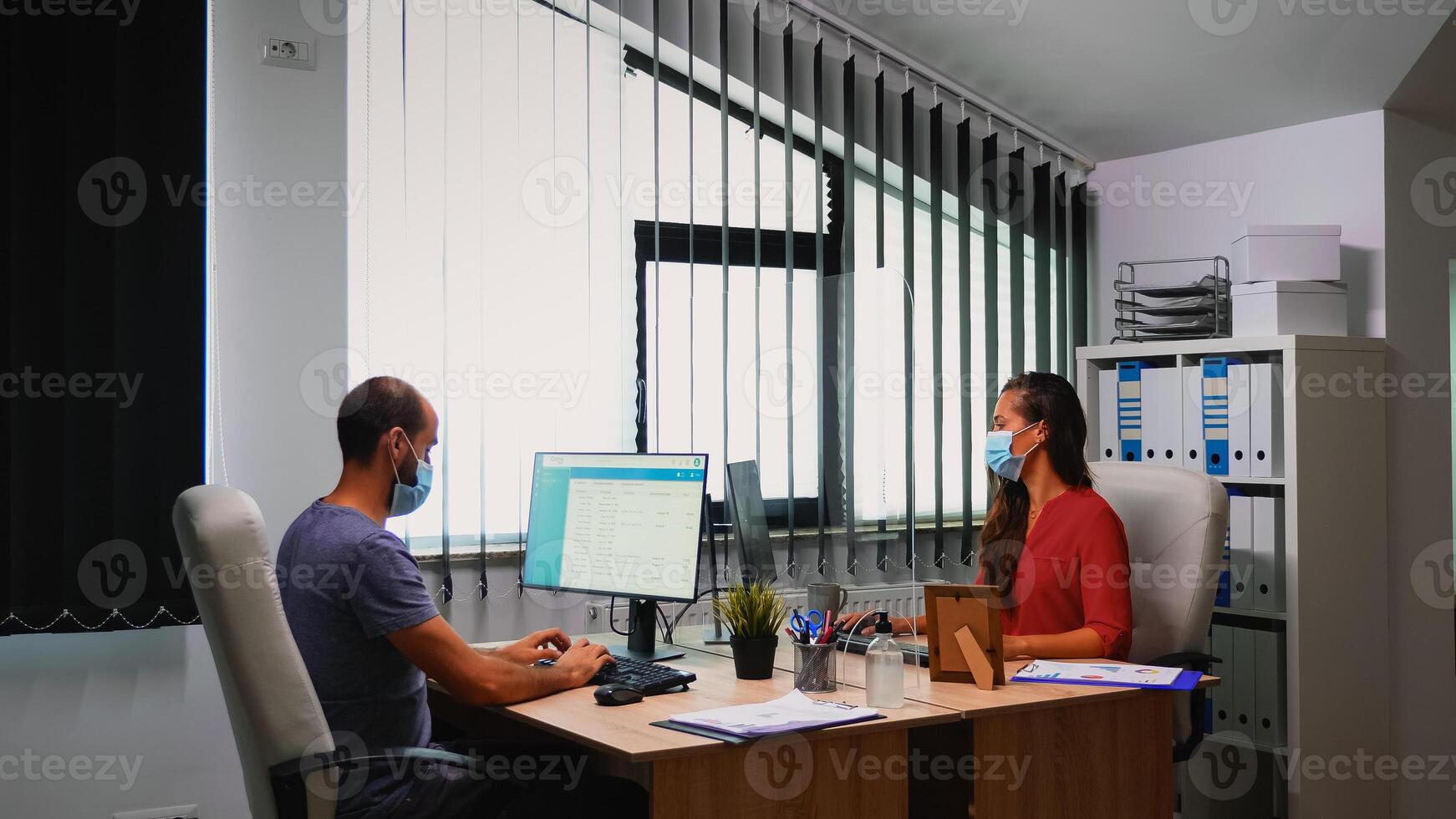 People sanitizing hands by alcohol gel before typing on keyboard. Employees working in new normal office workplace in company disinfecting hands using antibacterian gel against corona virus. photo