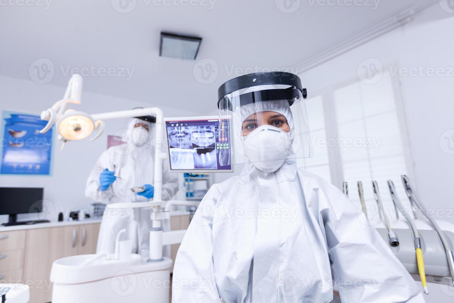 Patient first person view of dentist looking down in covid hazmat suit treating teeth. Stomatolog wearing safety gear against coronavirus during heatlhcare check of patient. photo