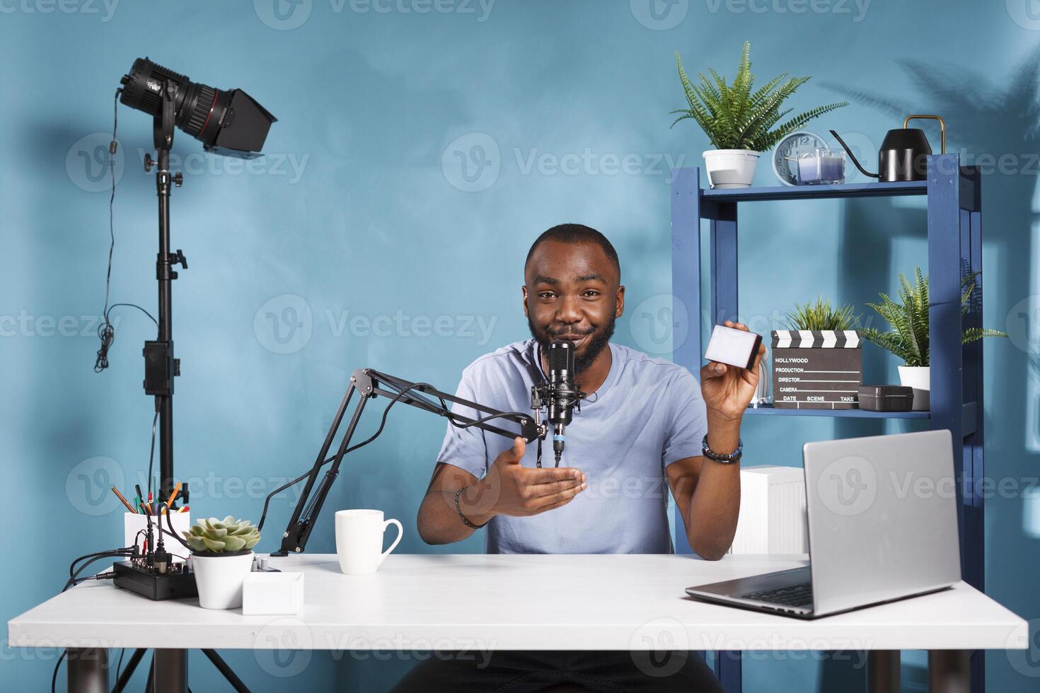 Vlogger talking about camera lighting equipment while recording video review for internet channel. Smiling african american videographer testing and recommending camera gear photo