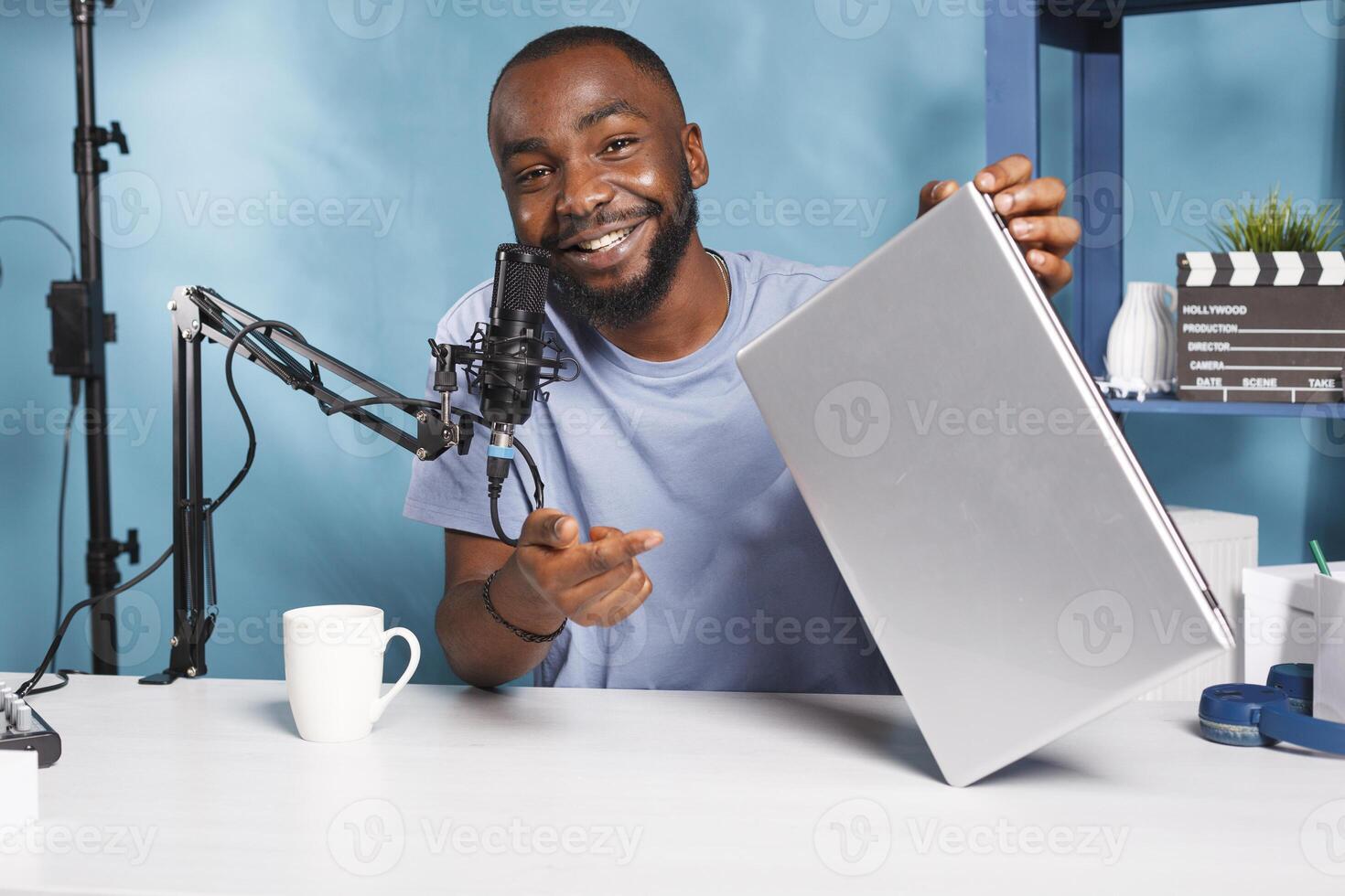 sonriente africano americano blogger participación ordenador portátil y grabación producto vídeo presentación. social medios de comunicación hombre de influencia revisando nuevo portátil computadora, mirando a cámara y transmisión foto
