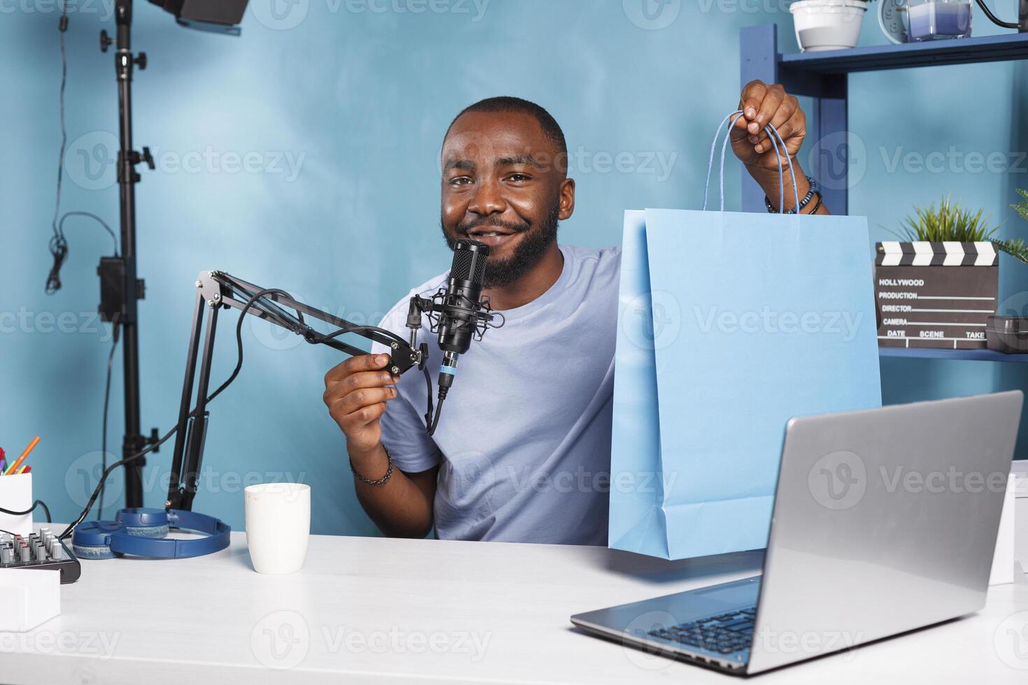Young influencer speaking about giveaway on stream and showing paper package portrait. Smiling african american blogger recording product promotion video while looking at camera photo