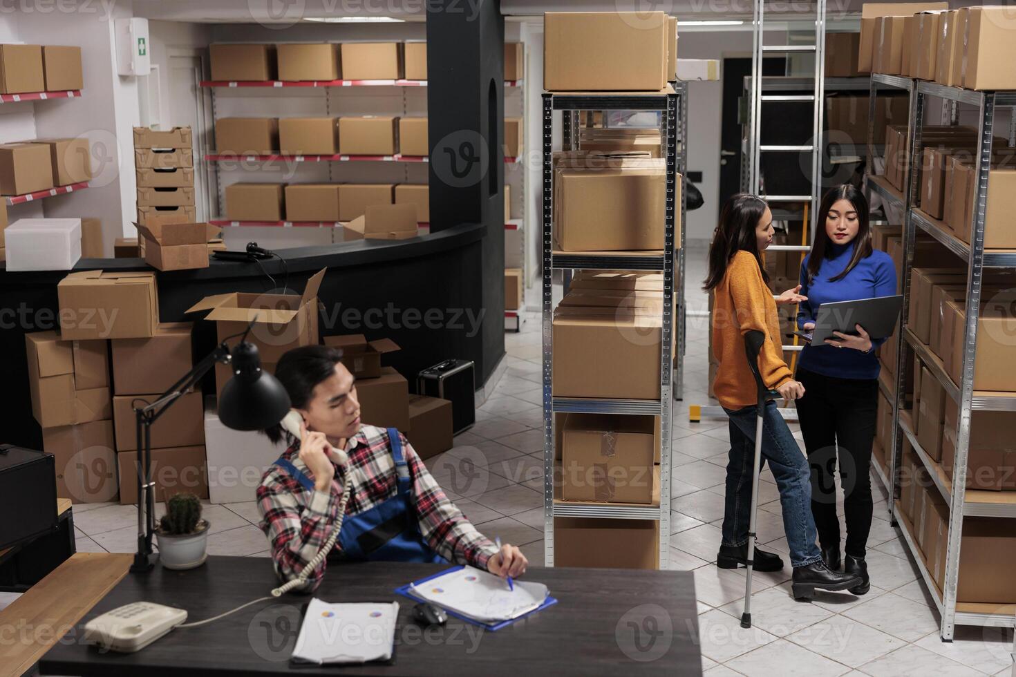 Delivery operators managing warehouse product audit in storage room. Retail industry storehouse employees working together, tracking parcel transportation online on laptop photo