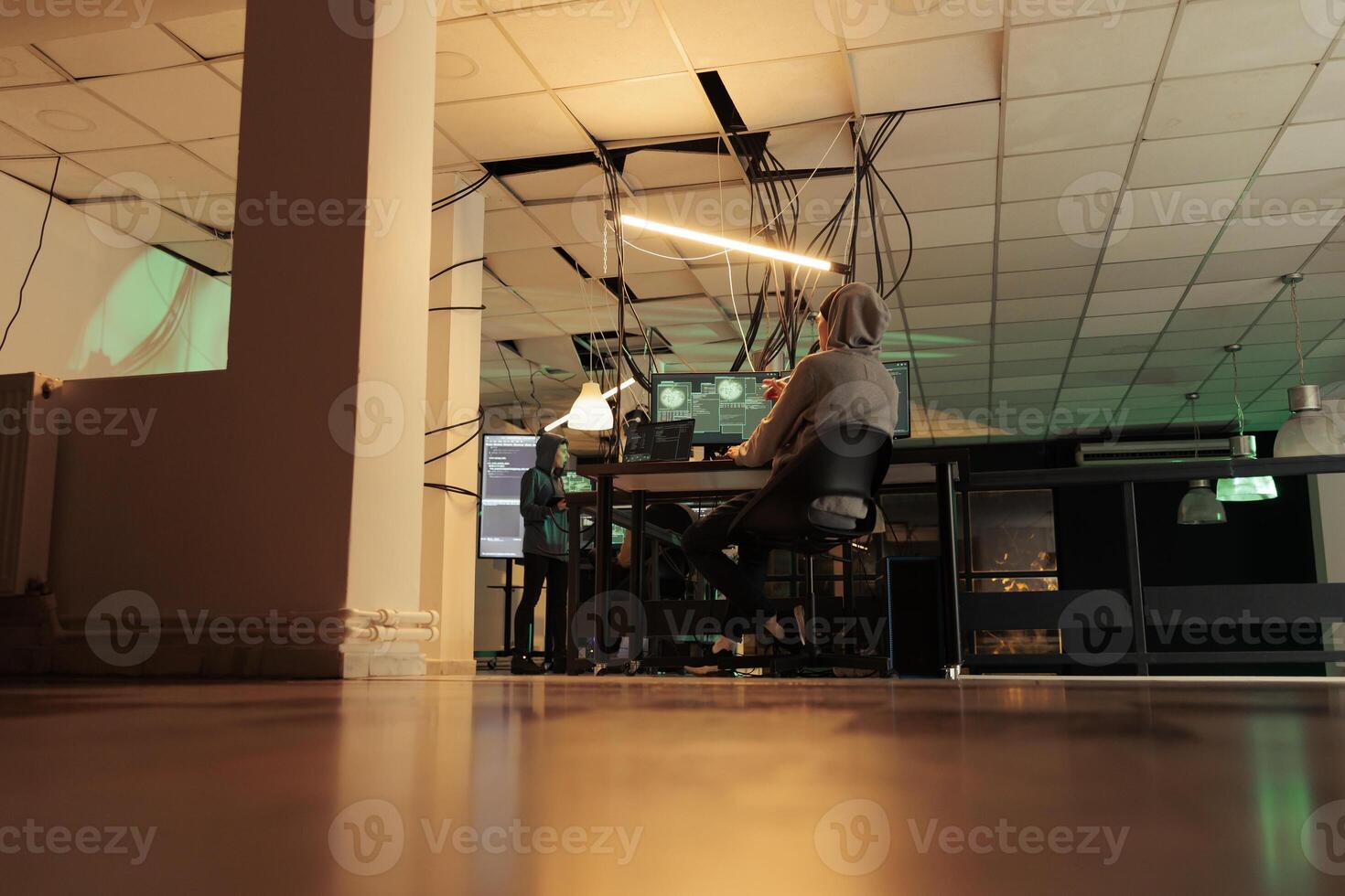 Diverse team of spies coding online virus program, stealing private information and passwords. Cybercriminals working together on identity theft and asking for ransomware at night. photo