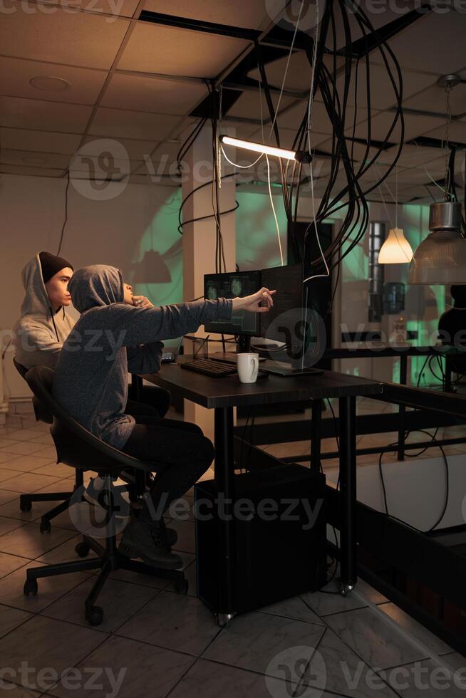 Man and woman hacking professional network to steal sensitive data, using malware for phishing. Team of spies trying to crack encryption, hacking cyberspace with virus. Leak information. photo