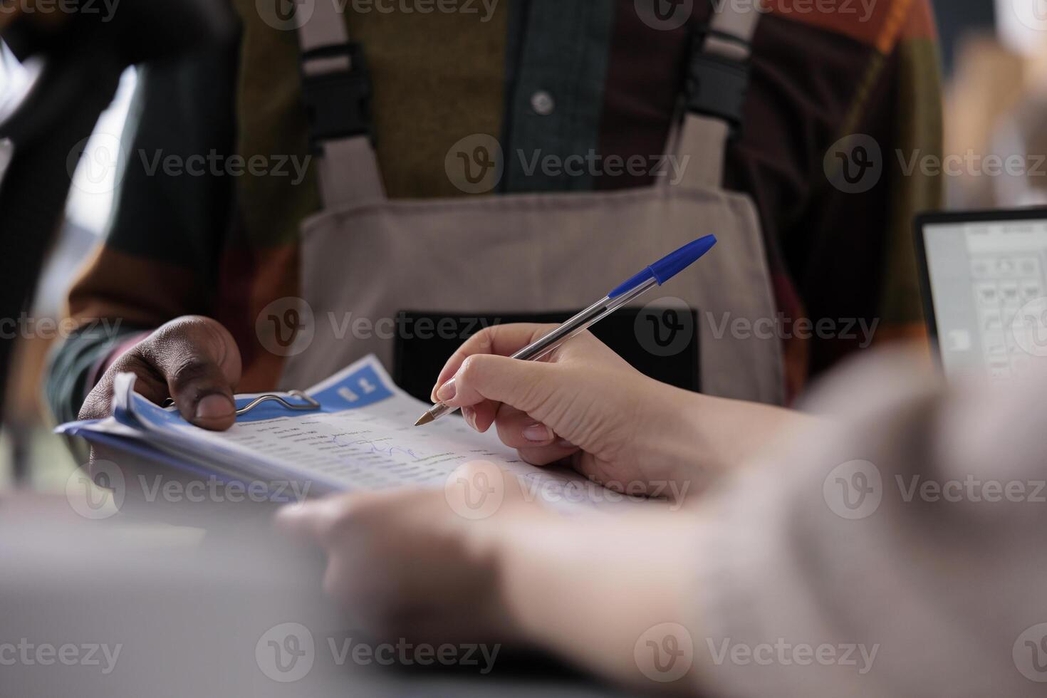 Storehouse supervisor signing packages shipping report, discussing customers orders with african american employee in storage room. Diverse team working at goods inventory in storehouse photo