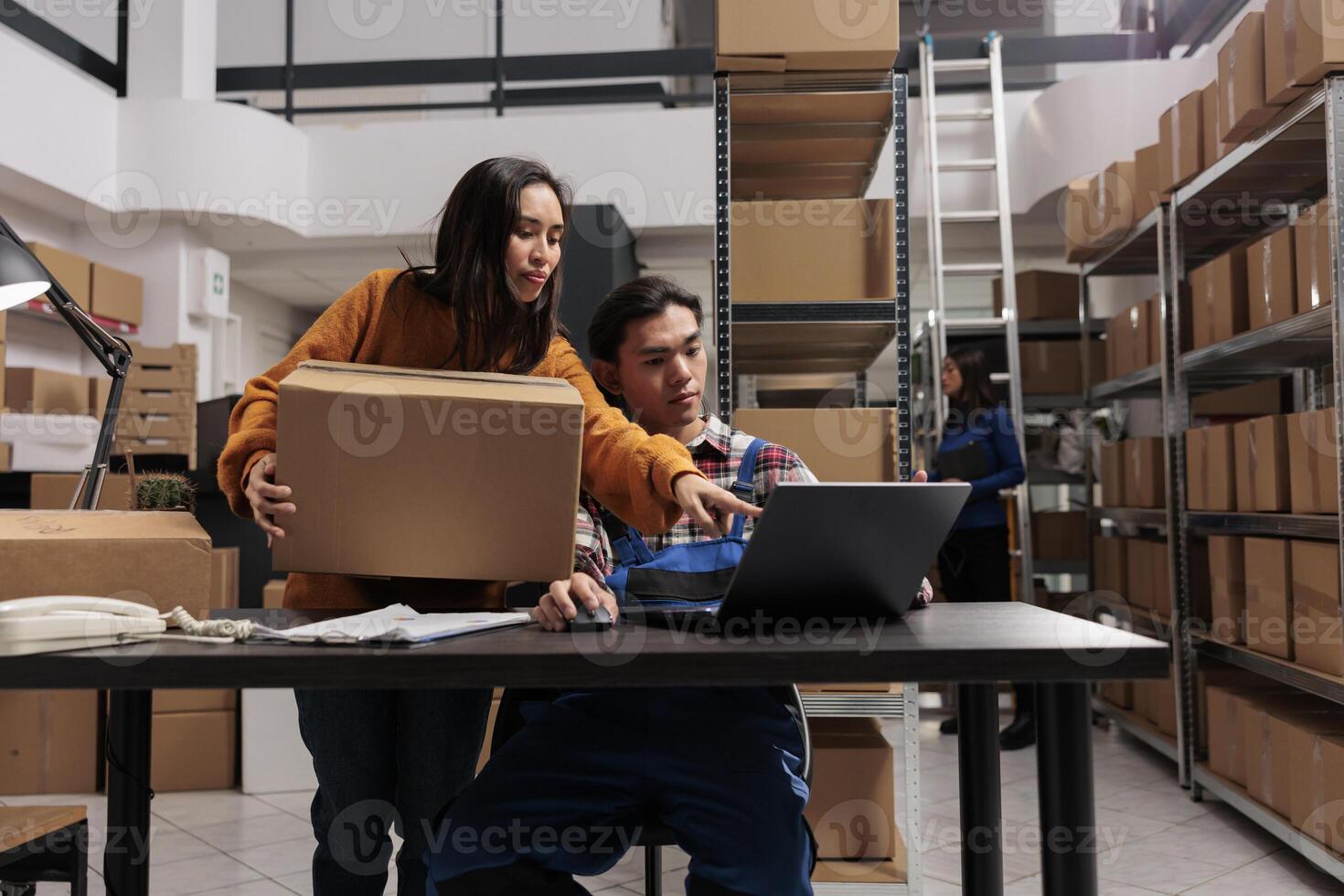 Shipment service workers managing parcel receiving and sending operations in post office storage room. Industrial warehouse asian workers team supervising goods inventory using computer software photo