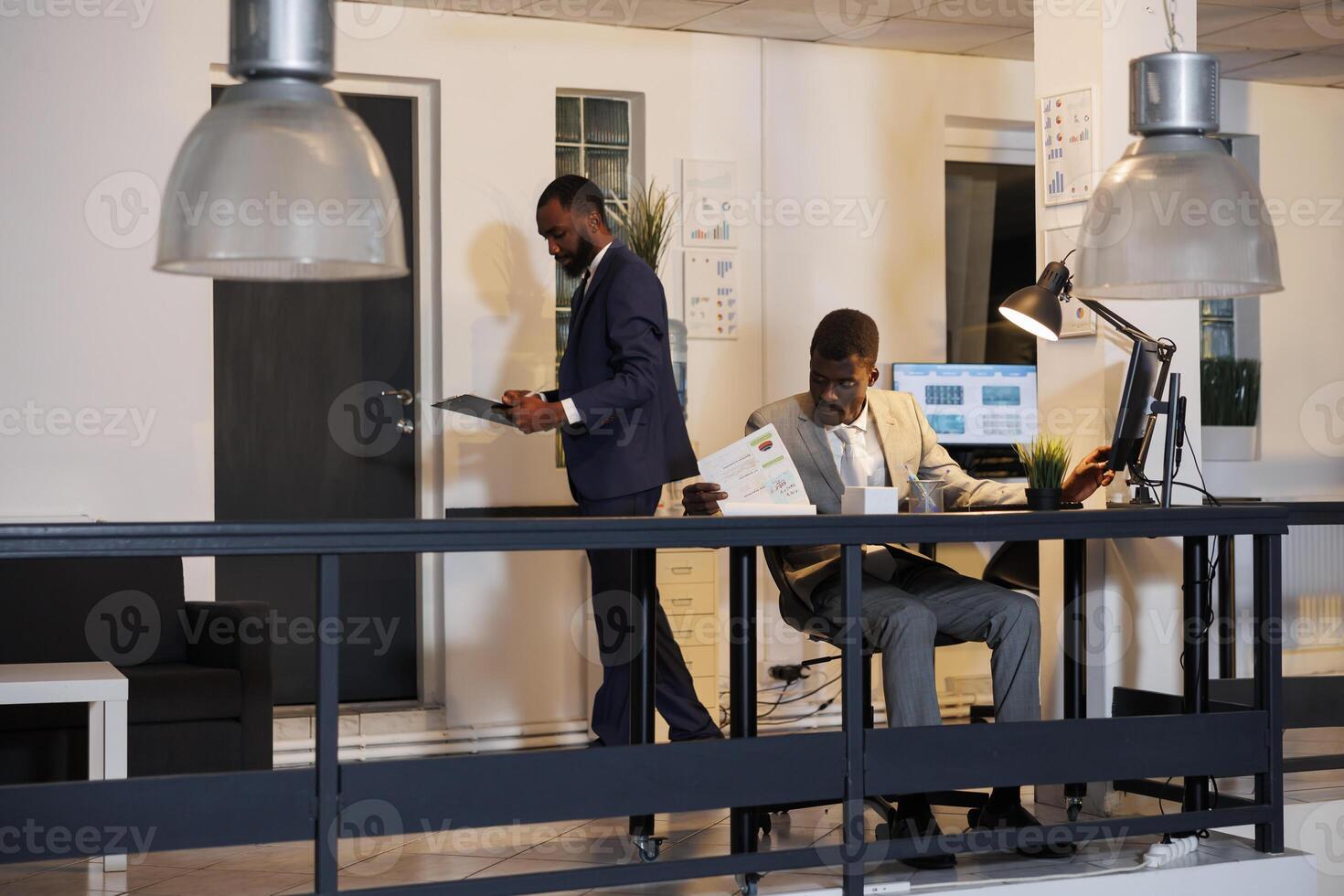 Executive manager sitting at desk in startup office, analyzing financial graphs report typing company strategy. African american entrepreneur working overhours at investment report. Business concept photo