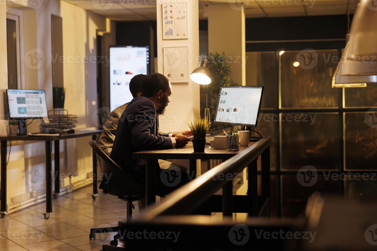 Corporate coworkers discussing marketing strategy, looking at financial report statistics on computer, working late at night in startup office. Workers brainstorming ideas for company investment plan photo