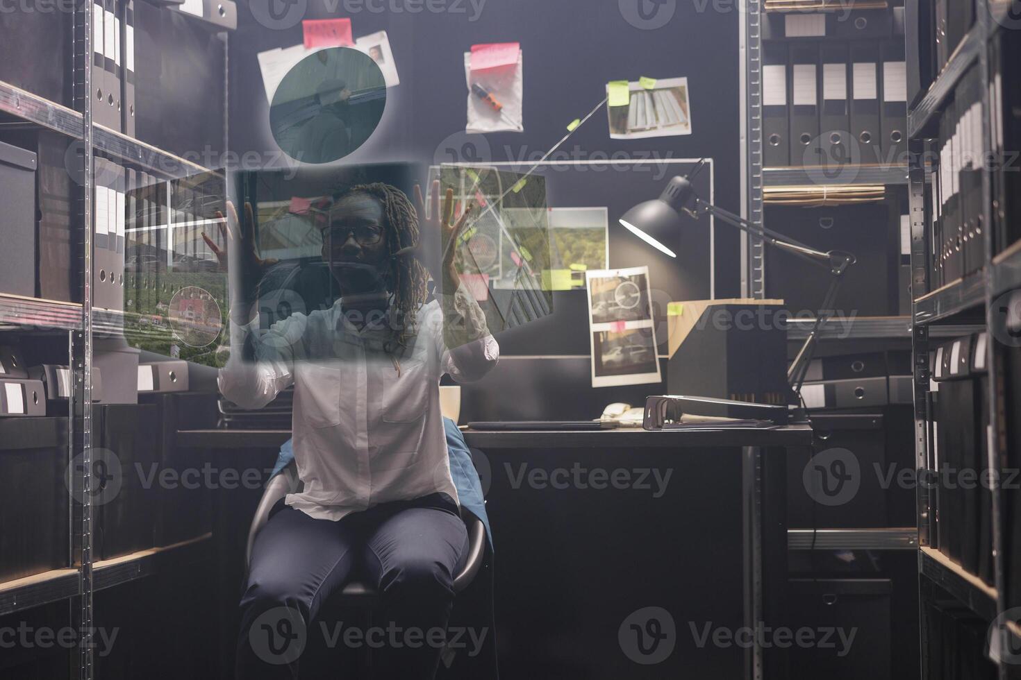 Young policewoman looking at clues in hologram, examining augmented reality holographic photos to solve felony in police archive room. Private detective working with artificial intelligence.