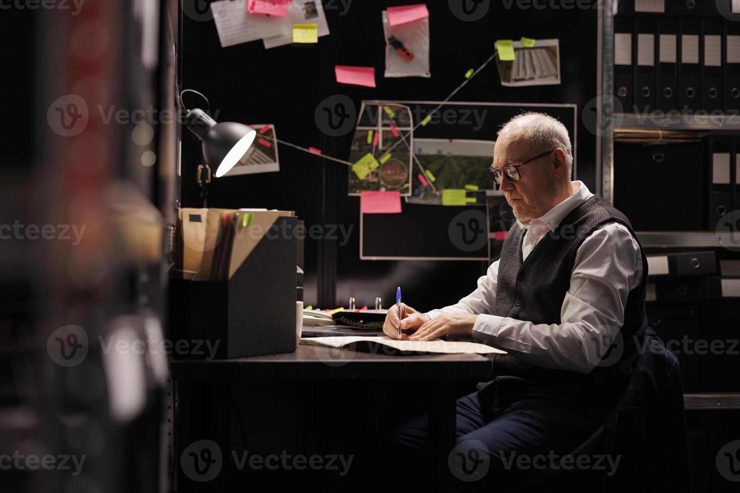 Tired elderly private detective in formal suit working overtime at criminal case in arhive room. Overworked police officer analyzing criminology report, checking federal investigations evidence photo