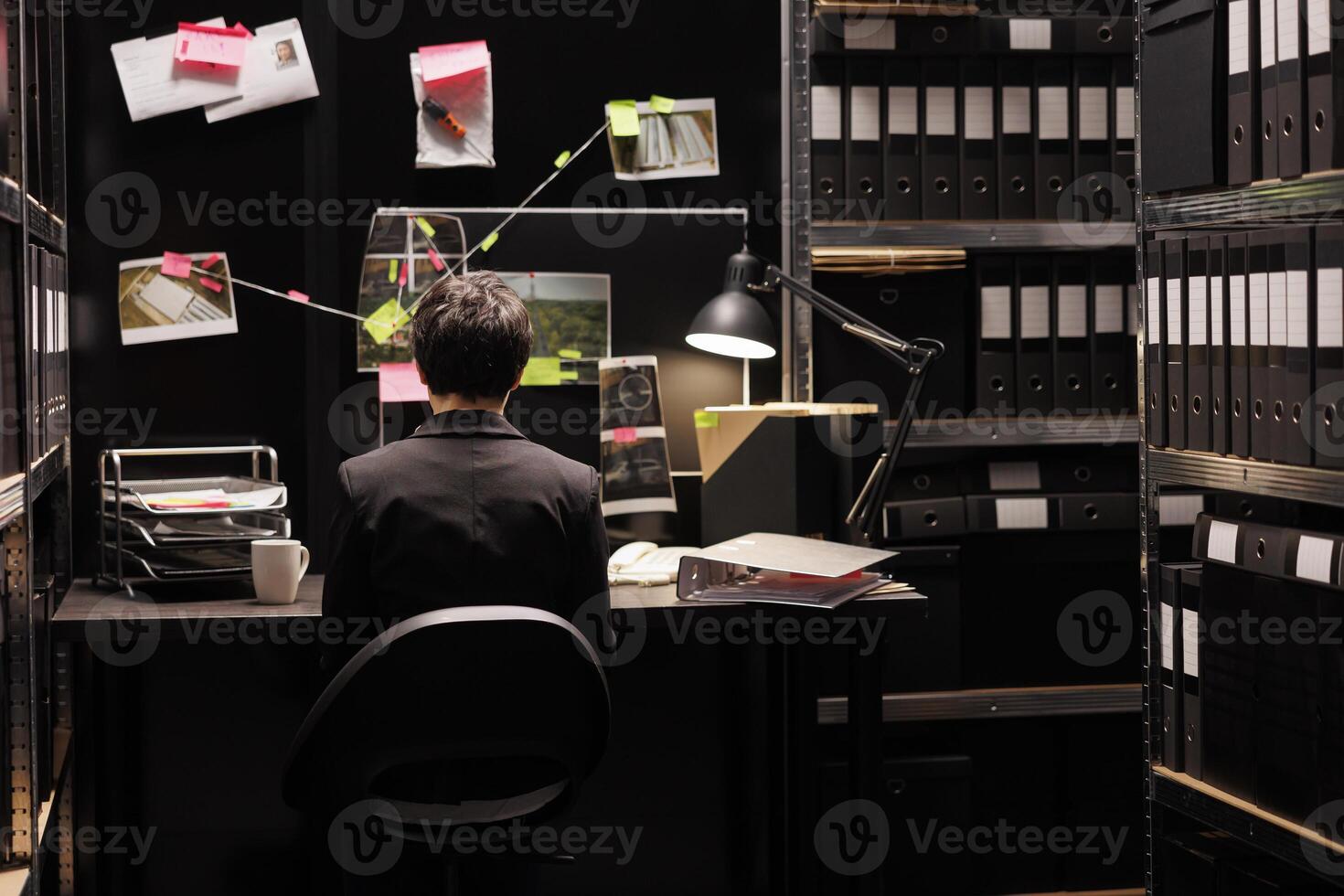 Agency investigator sitting at desk in federal bureau late at night, working at criminal case analyzing suspect evidence. Police officer reading fbi confidential report discovery secret investigation photo