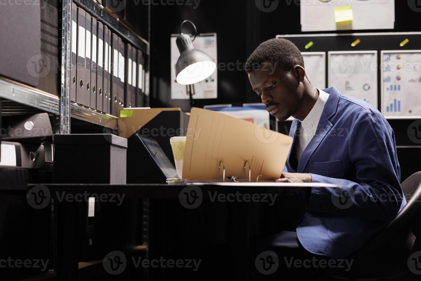 Police officer holding document with confidential case, reading victim information in federal agency. African american private detective checking crime scene evidence, analyzing surveillance data photo