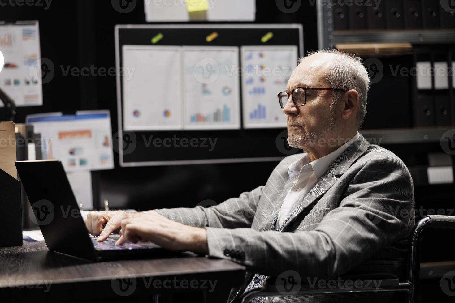 Senior accountant in wheelchair checking administrative analytical data in cabinet room office surrounded by accountancy statistic reports. Professional businessman in file storage room photo