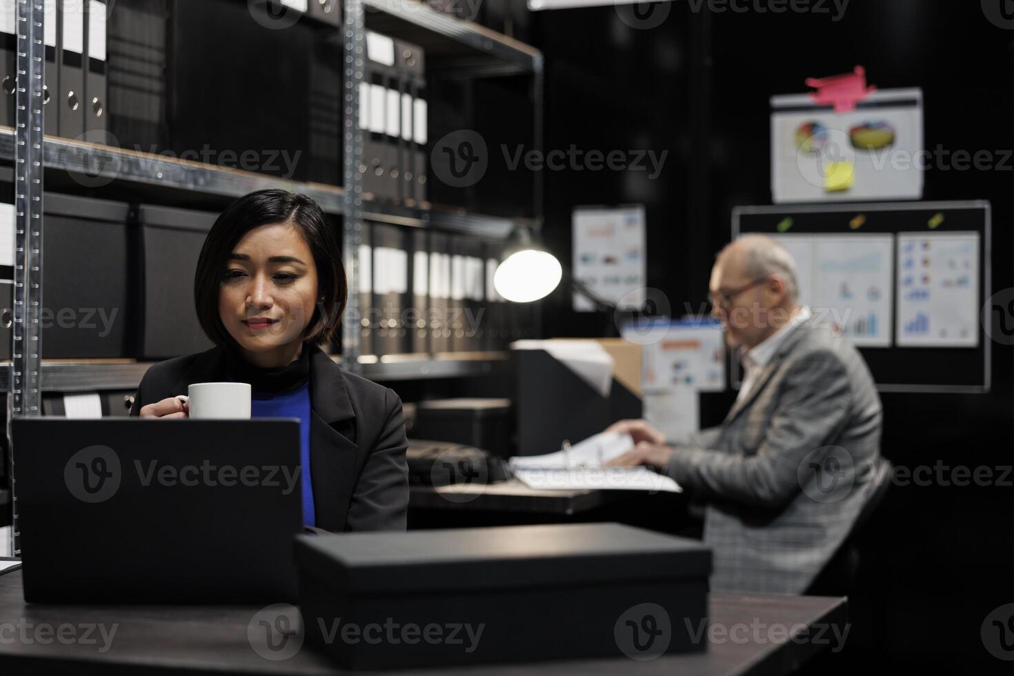 Bookkeeping employees in consultancy bureaucratic workplace filled with business folders. Employees working in administrative file room office surrounded by statistical chart graphics. photo