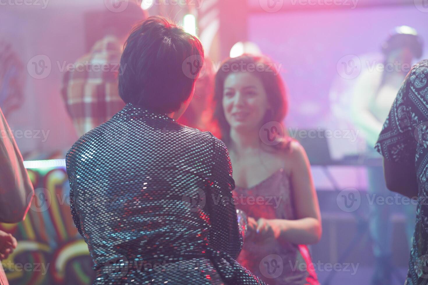 Women talking while relaxing at discotheque party in nightclub. Girlfriends having conversation and enjoying nightlife leisure while clubbing and attending disco gathering in club photo