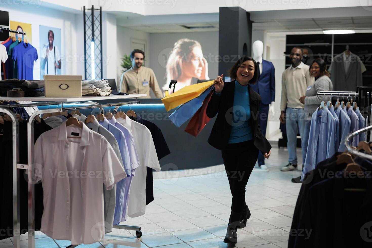 Clothing store satisfied customer walking with shopping bags in clothing store and looking at camera. Cheerful smiling asian woman carrying paper bags with trendy apparel purchase in mall photo