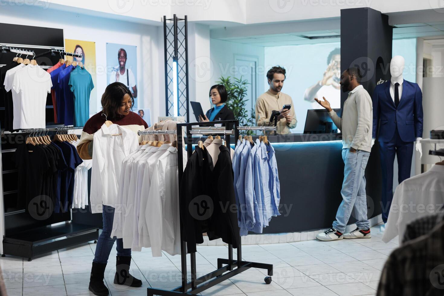 African american woman browsing rack with white shirts and selecting size in clothing store. Customer holding formal wear apparel and examining fit while shopping in fashion boutique photo