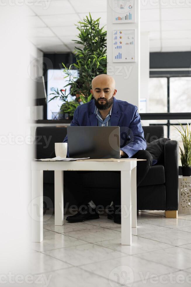 Arab man startup business employee typing on laptop, analyzing marketing campaign. Company executive manager planning product sales strategy while working in coworking open space photo