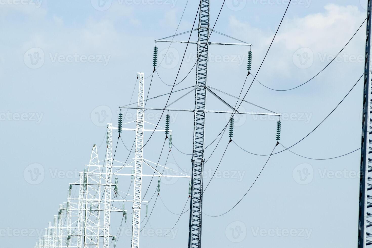 Supports high-voltage power lines against the blue sky with clouds. Electrical industry photo