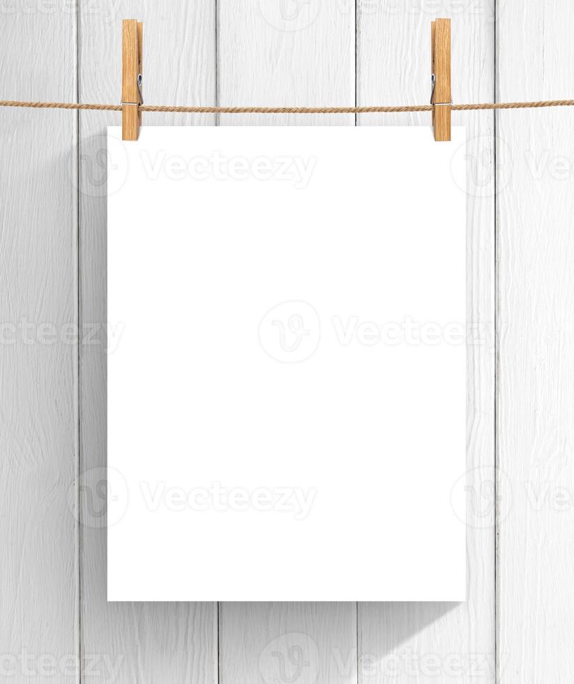 Empty sheet of paper hanging on the clothesline over wooden background. Mock up for your project with copy space photo