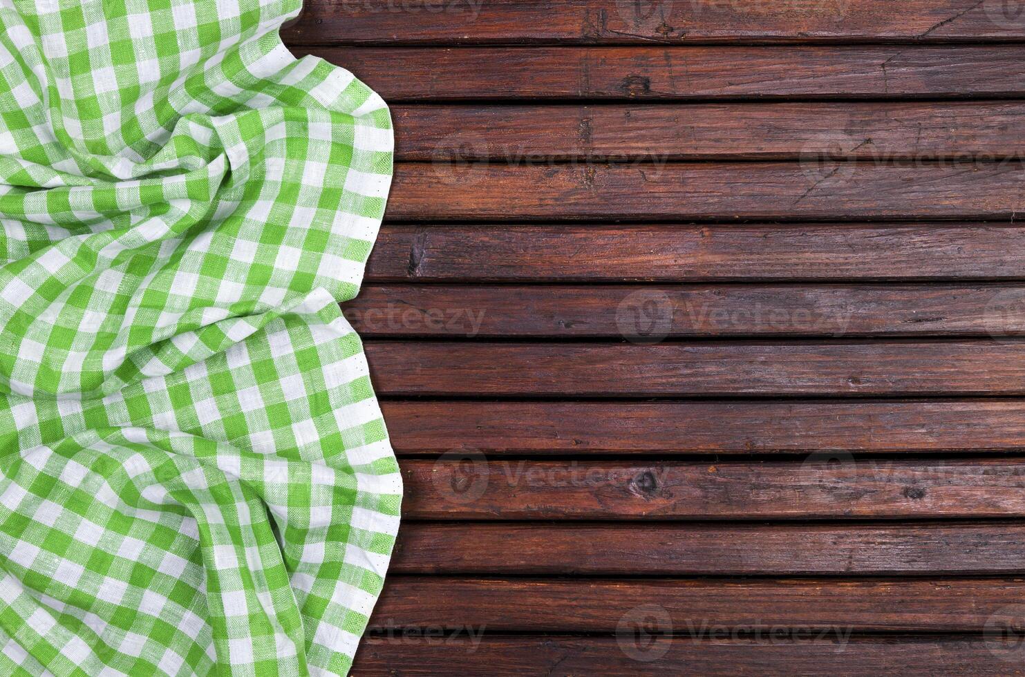 Green checkered tablecloth on dark wooden table with, top view with copy space photo