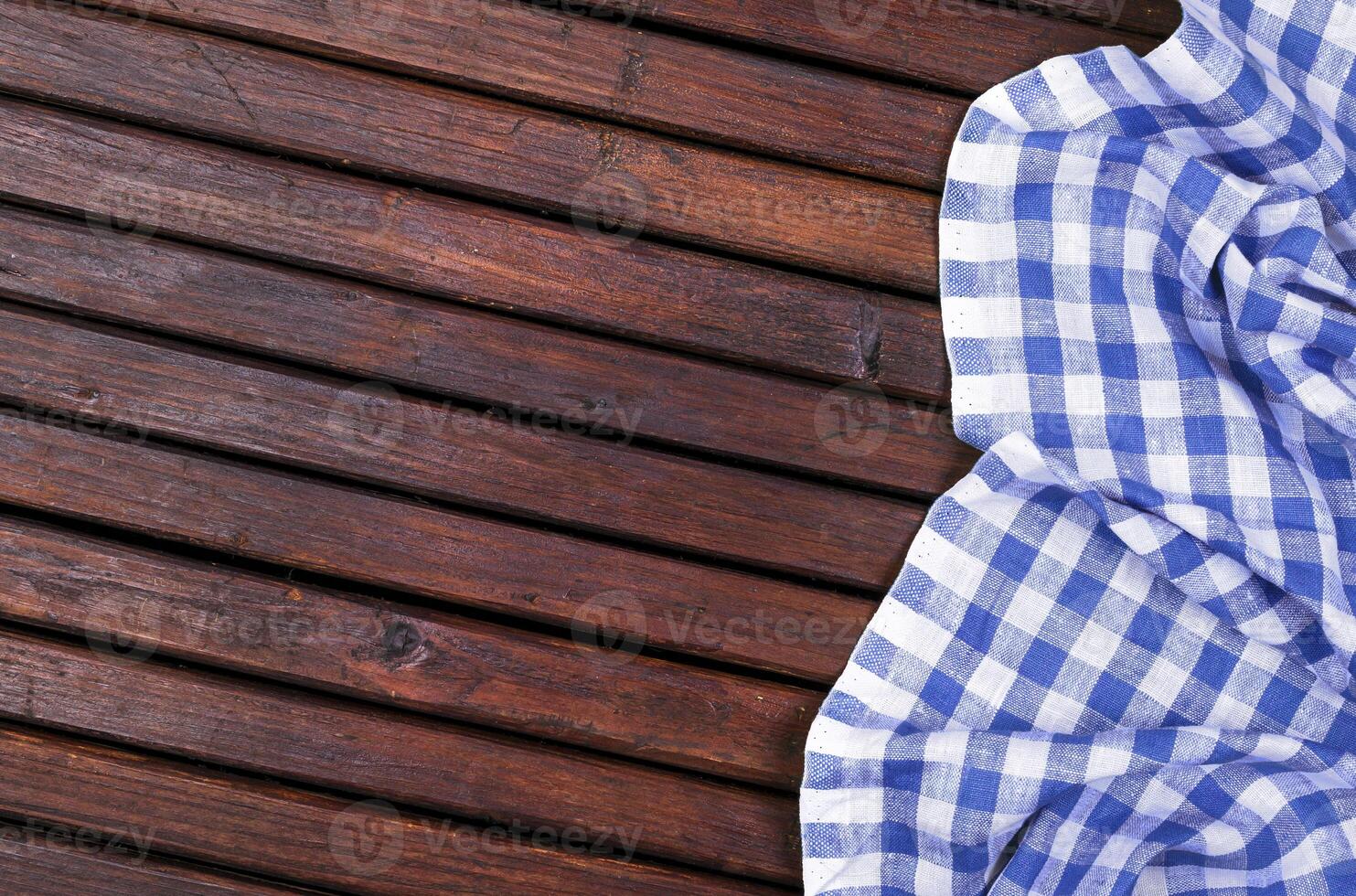 Dark wooden table with blue checkered tablecloth, top view with copy space photo