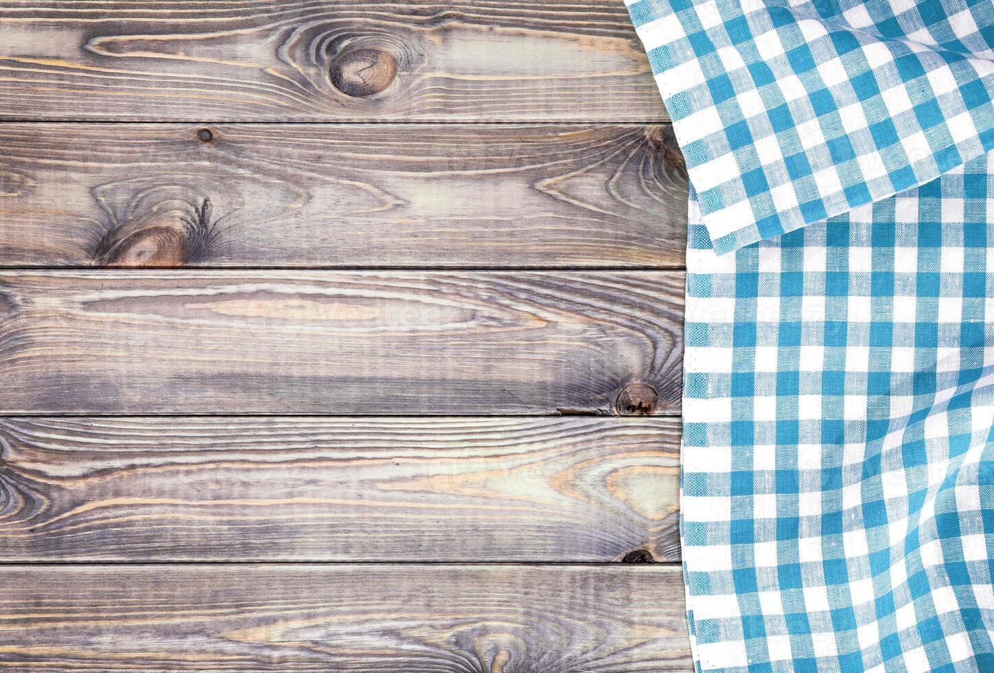 White old wooden table with blue checkered tablecloth, top view with copy space photo