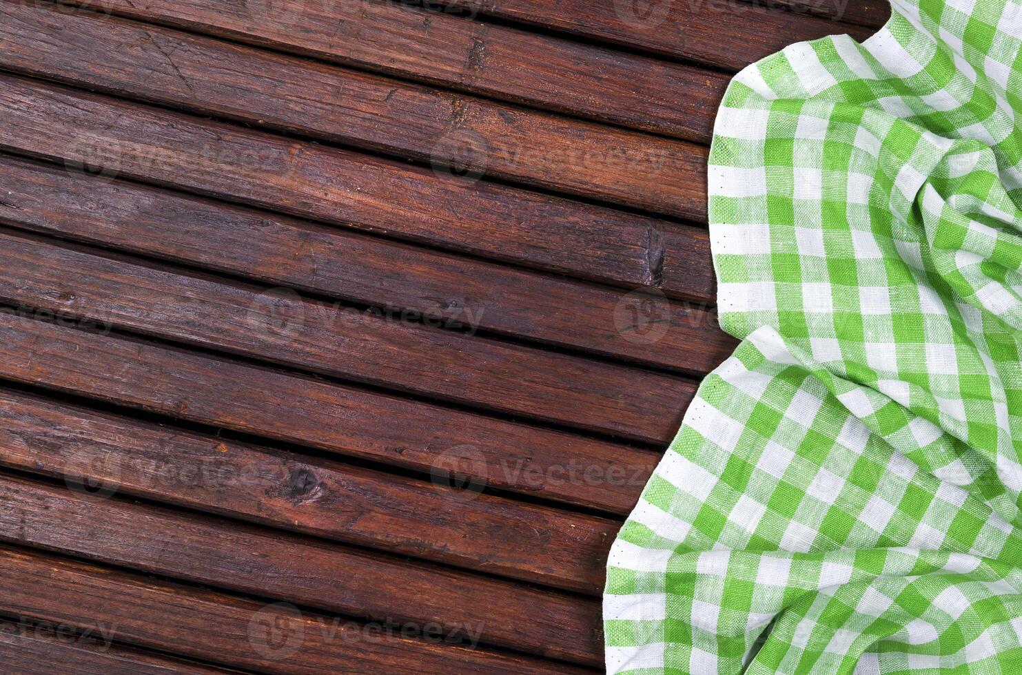 Green checkered tablecloth on dark wooden table with, top view with copy space photo