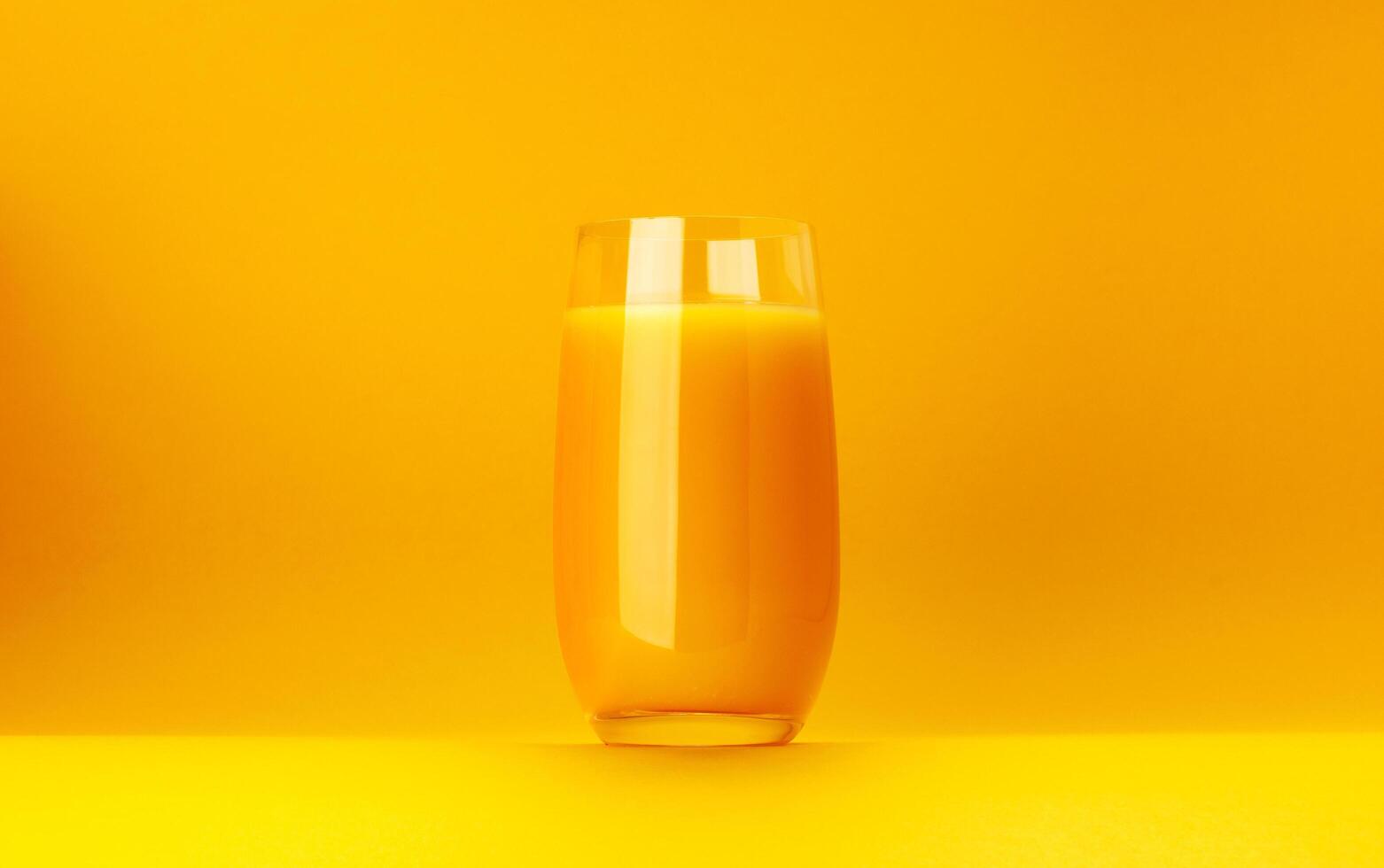 Glass of orange juice isolated on yellow background with copy space photo
