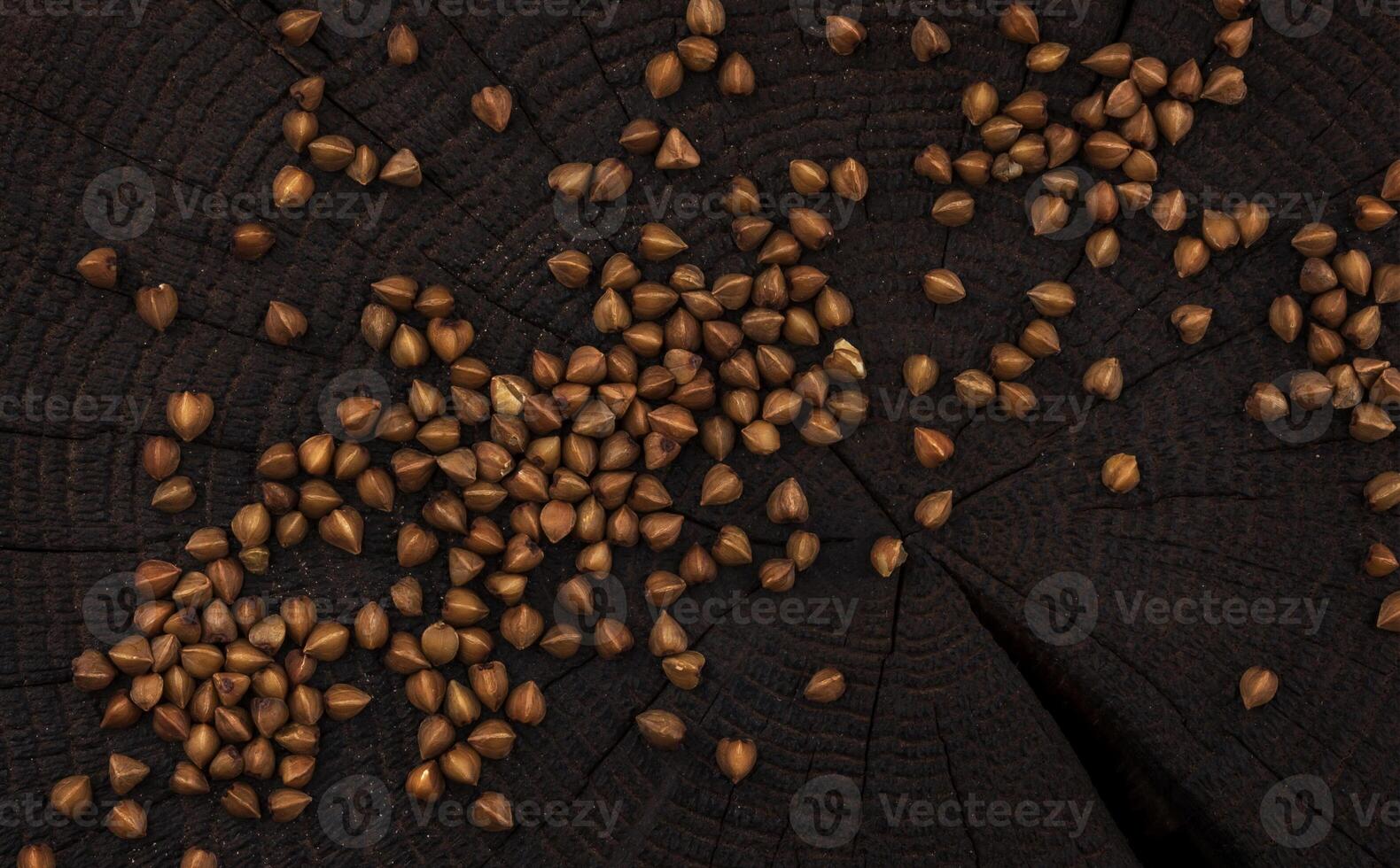 Heap of buckwheat grain on black wooden background. Top view photo