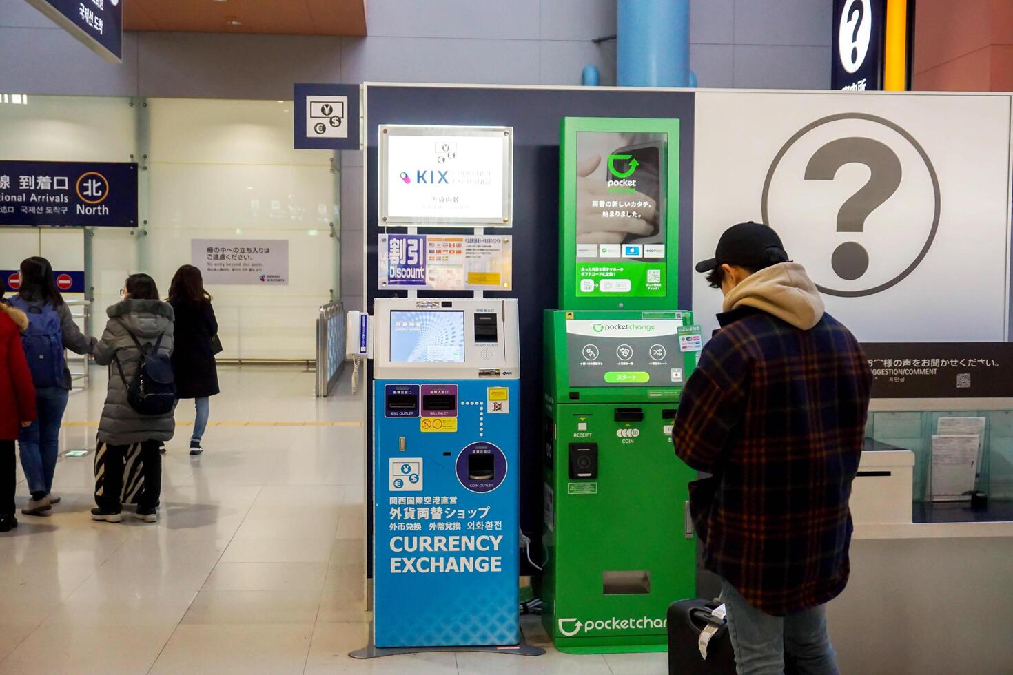 Osaka City, Japan, 2023 - Chinese tourist man are standing counting their own money to exchange money at automatic currency exchange machine in the Kansai International airport. photo