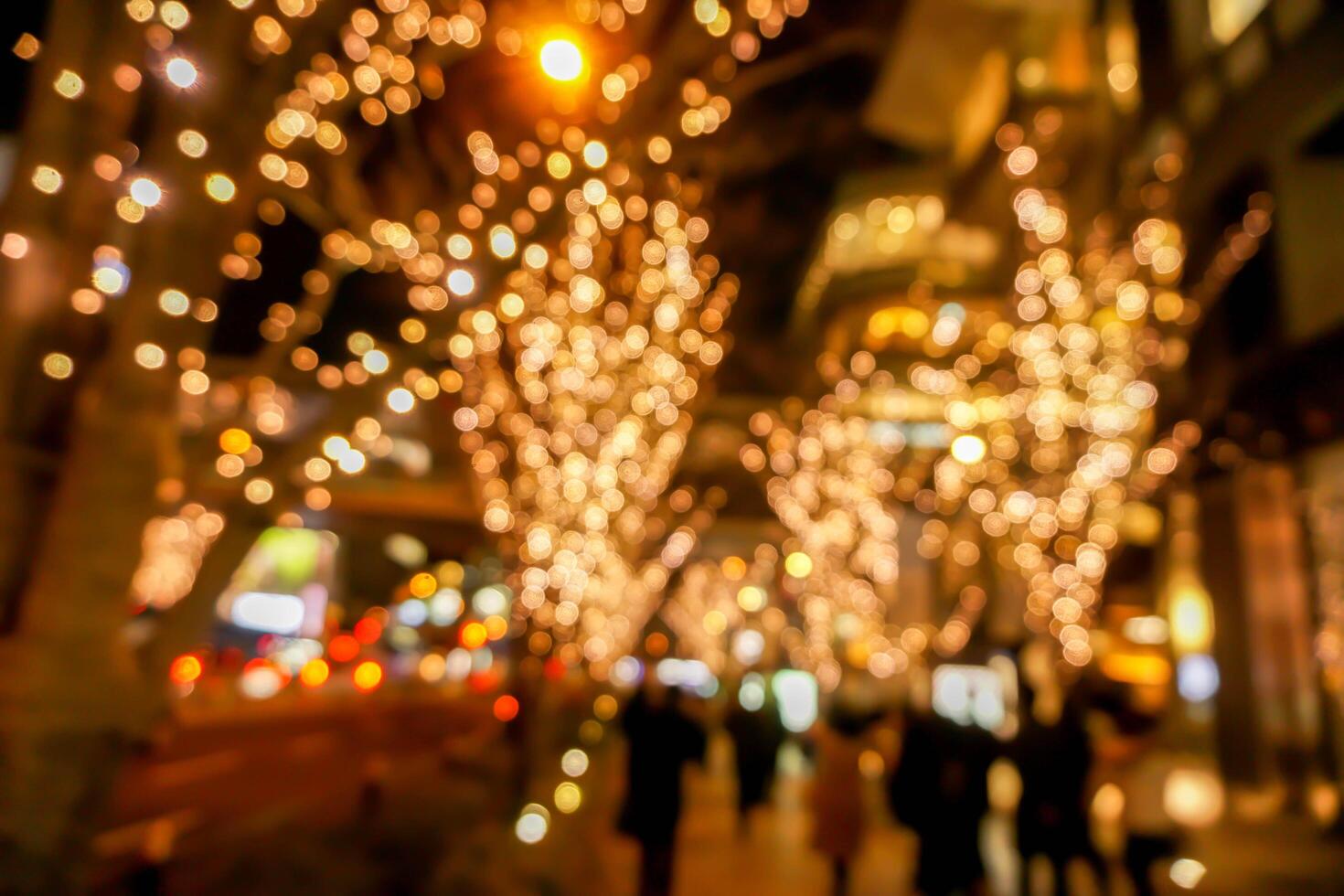 Blurred and bokeh of LED refection lighting on trees after Christmas and New Year with city night life in Osaka, Japan. photo