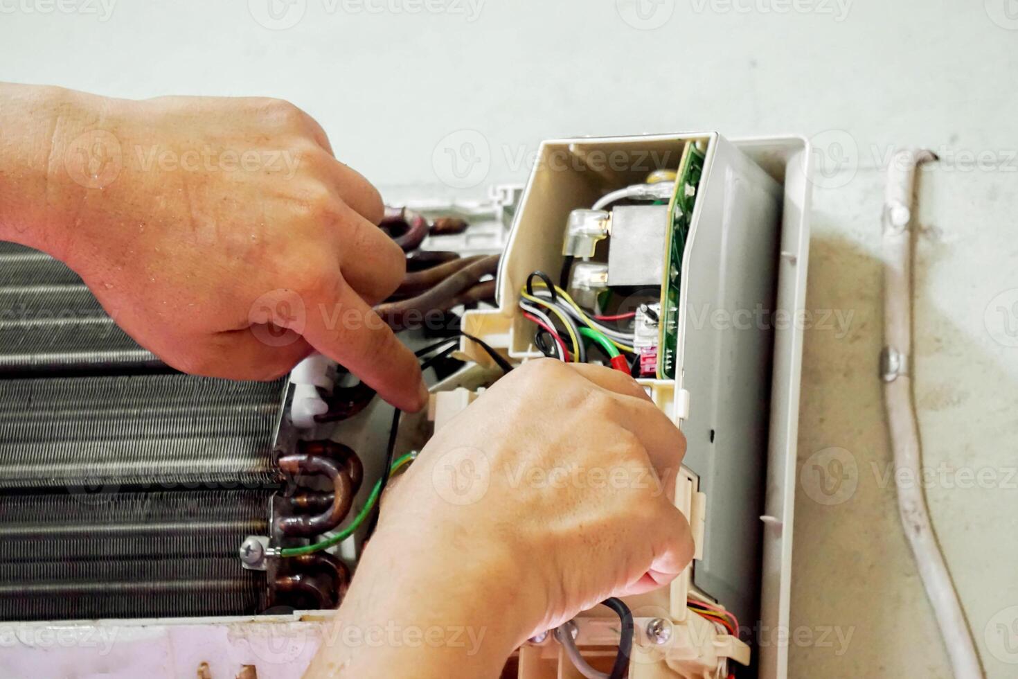 Closeup hands of electric repair technician fix an electronic board of home's air conditioner after washing in the bedroom. photo