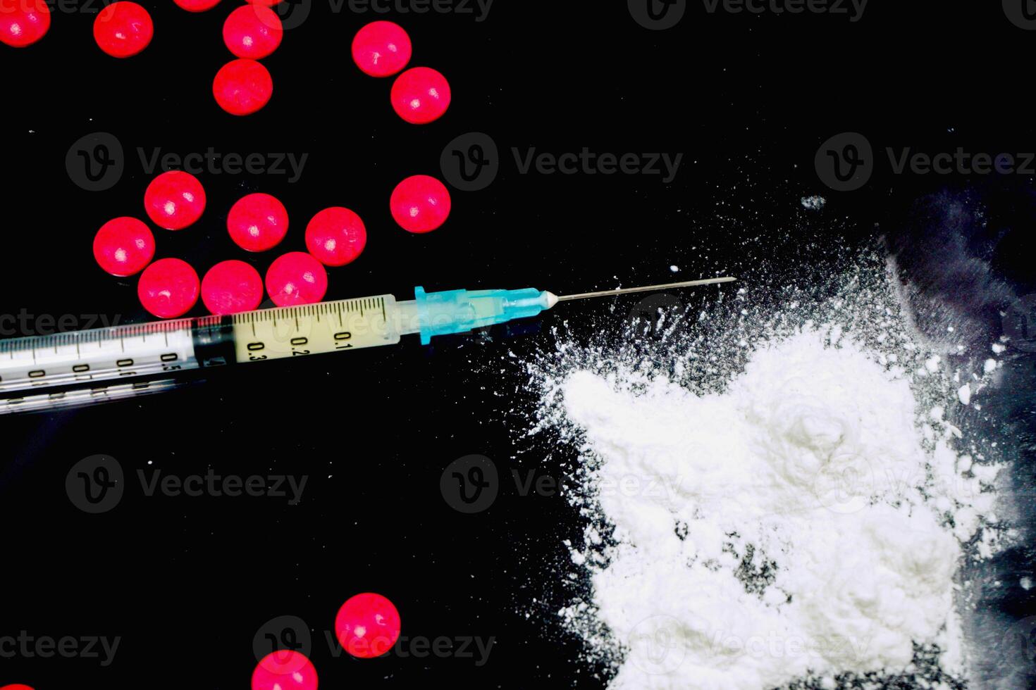 Top view and crop of plastic syringe in a medical needle and white powder with red pill medicine isolate on black background. Suppose to heroin and amphetamine or narcotic addiction. photo